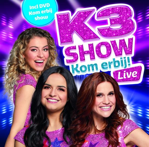 K3 Show albumhoes. Drie lachende vrouwen op een paars podium, met een showtitel en promotietekst.