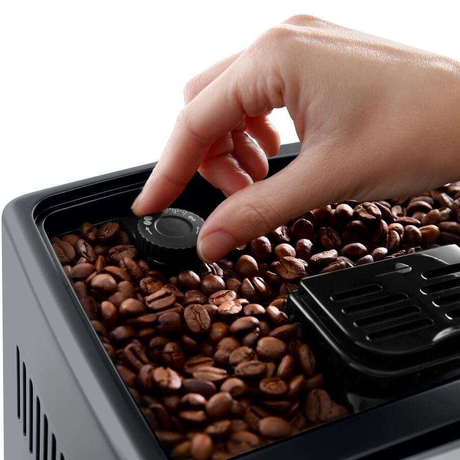 Eine Hand, die die Einstellung eines Kaffeemahlers vornimmt, mit Kaffeebohnen im Behälter.