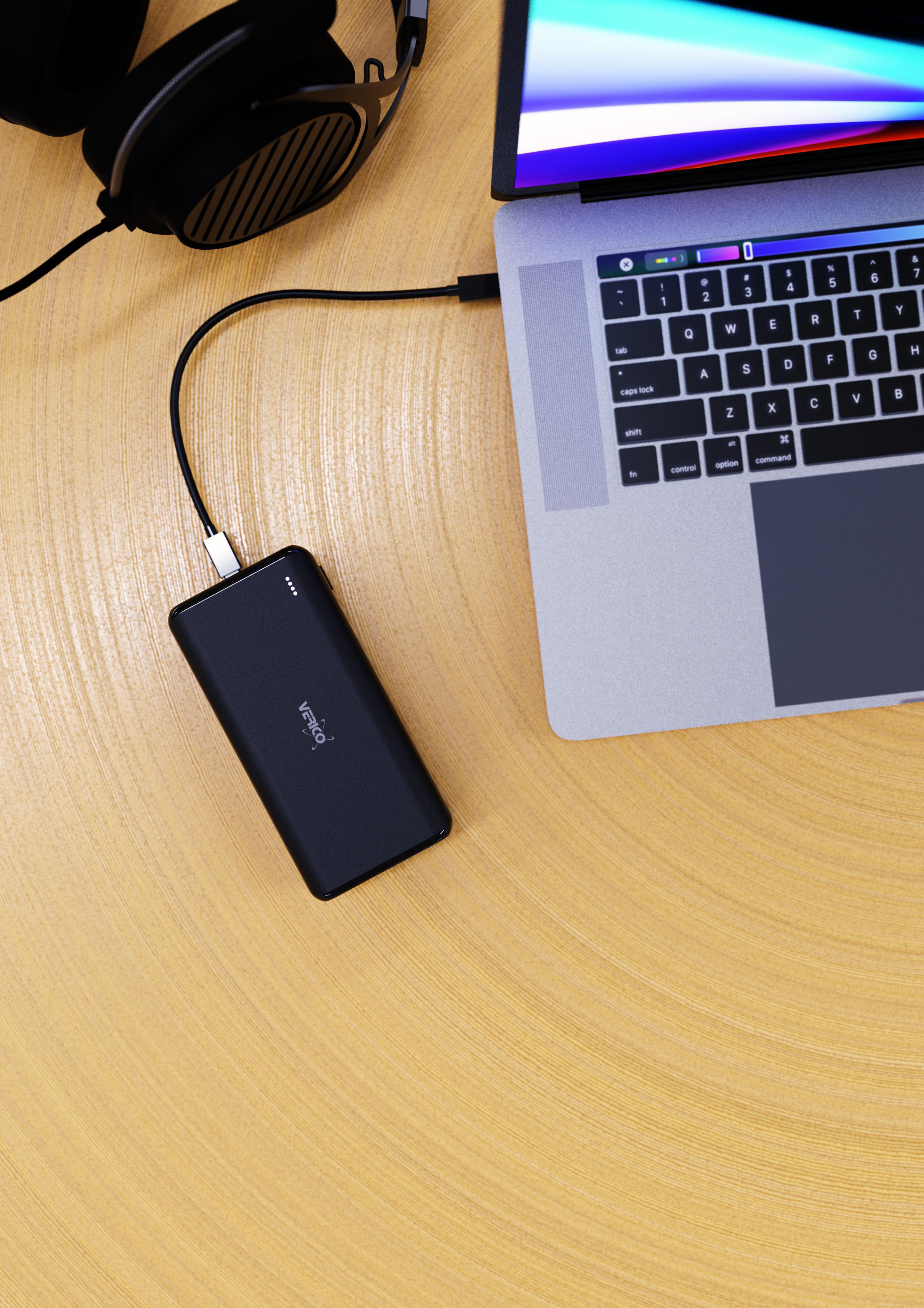 Laptop, der über ein USB-Kabel mit einer schwarzen Powerbank verbunden ist. Liegt auf einem Holztisch. Kopfhörer sind in der Nähe.