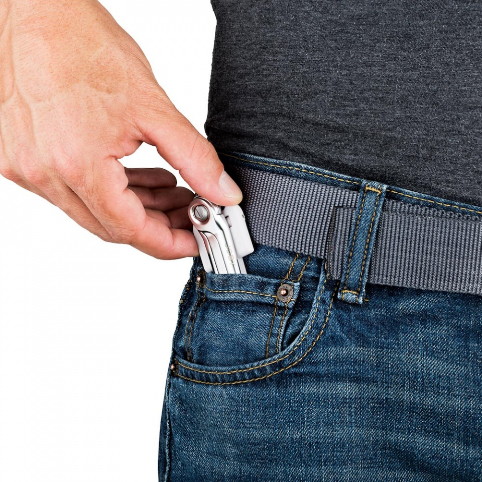 Une main s'insère dans une poche de jean pour sortir un multi-outil avec une poignée blanche.