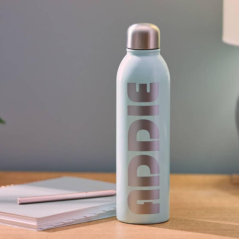 Eine blaue Wasserflasche mit dem Wort 'ADDIE' in Silber, auf einem Schreibtisch mit Notizblock und Stift.