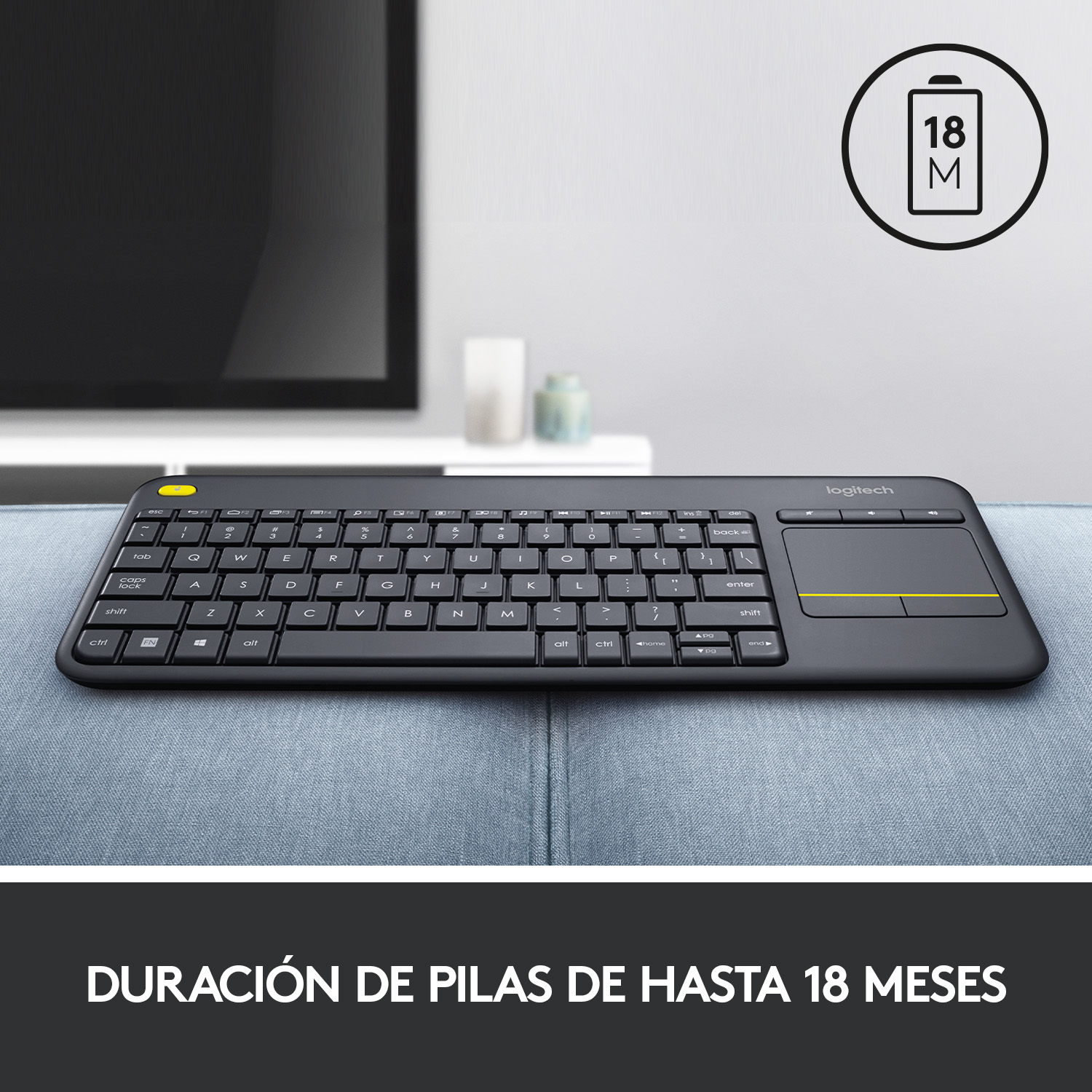 Un teclado Logitech negro con panel táctil, con un televisor al fondo.
