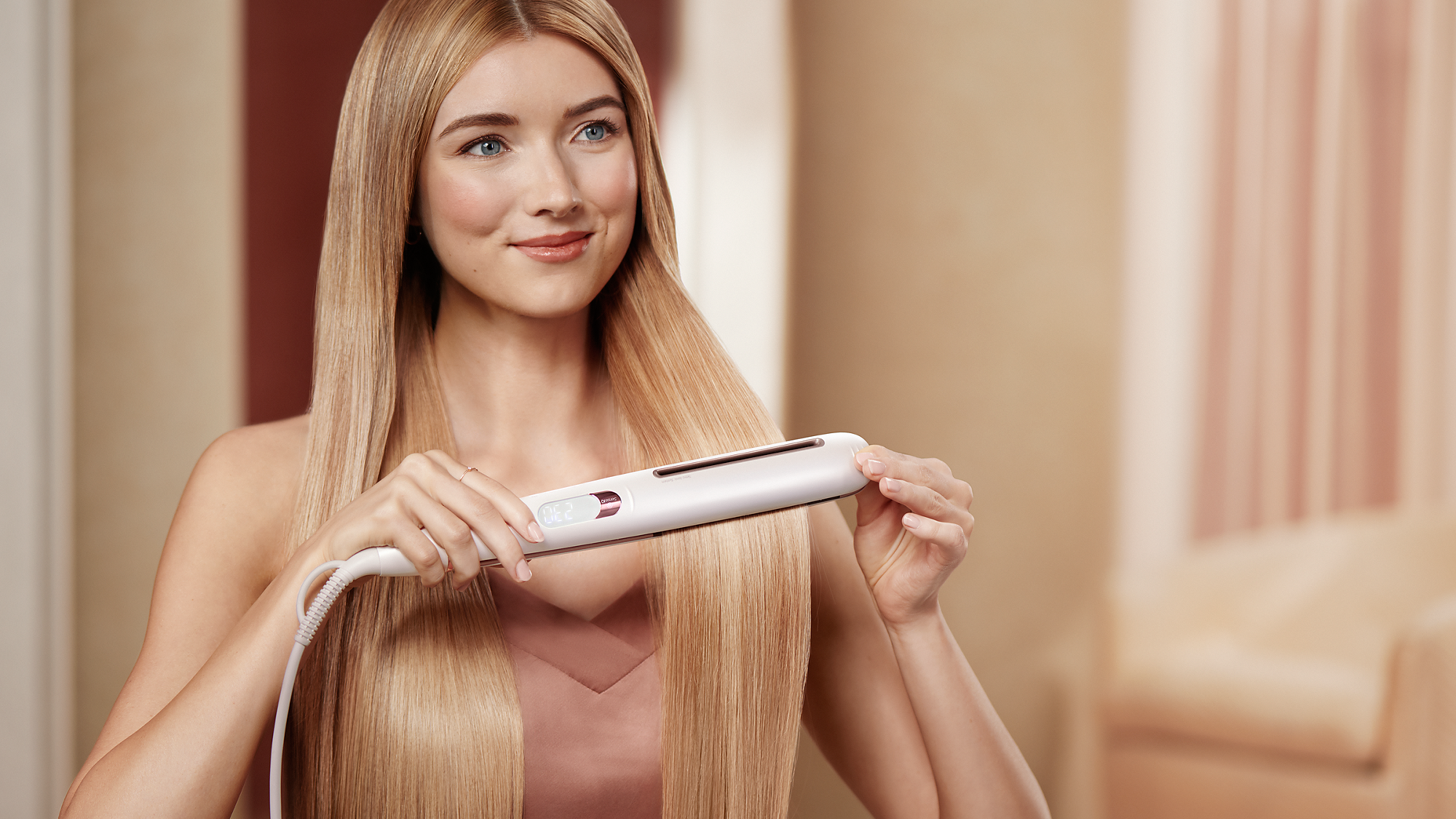 Frau mit glattem Haar benutzt einen Haarglätter.