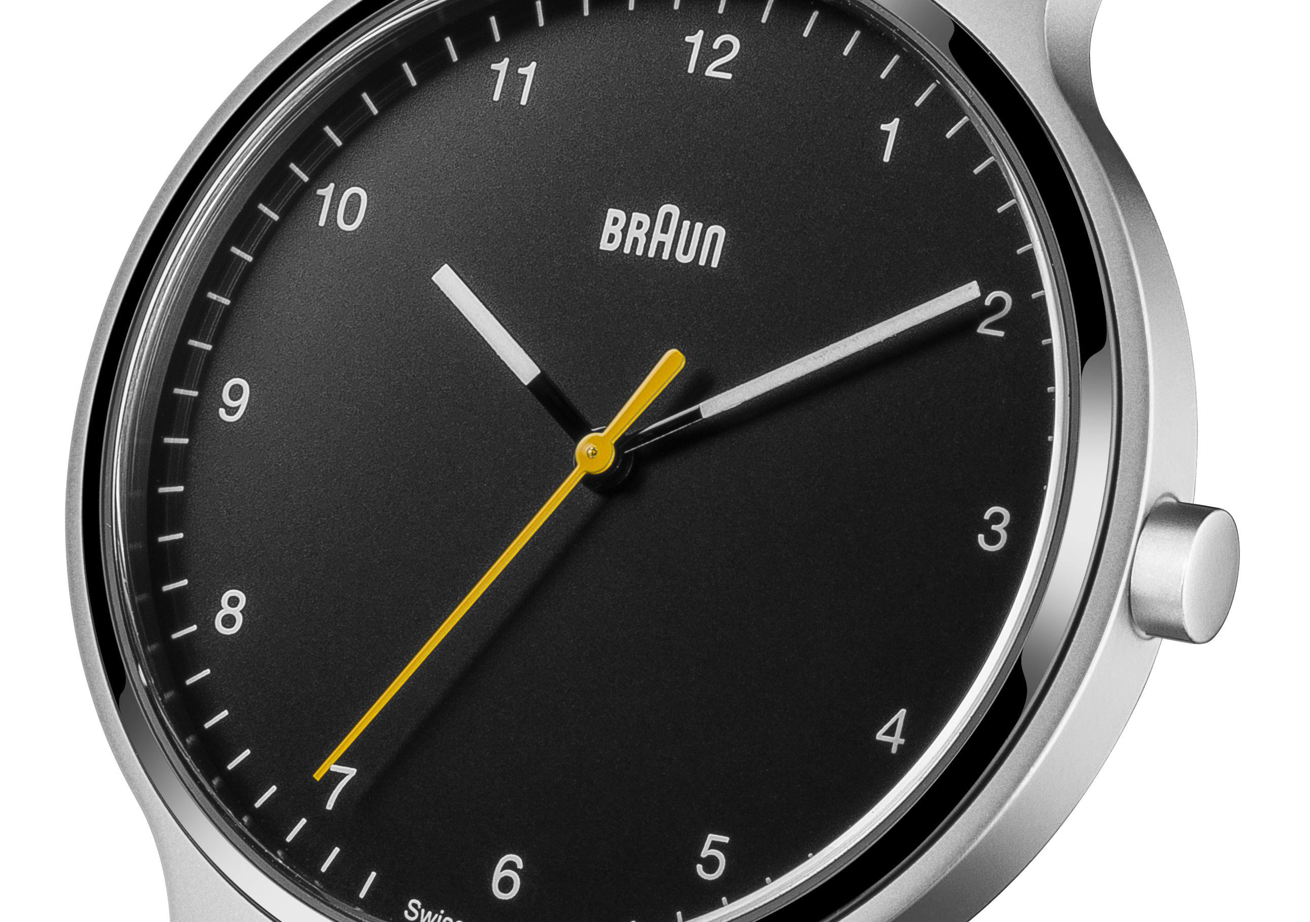 Nahaufnahme einer Braun-Uhr mit schwarzem Zifferblatt, silbernem Gehäuse und gelbem Sekundenzeiger.
