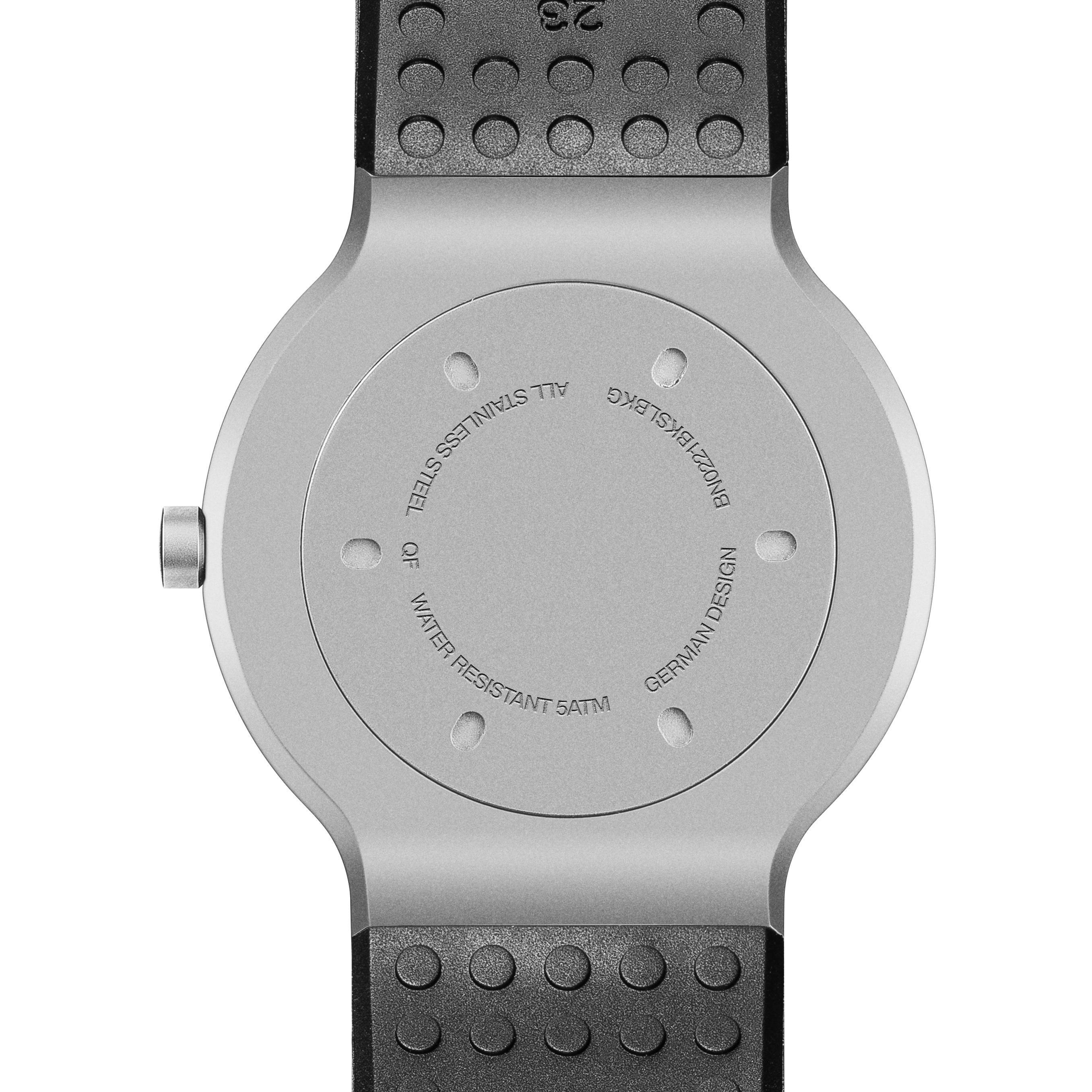 Rückseite der Uhr: silbernes Zentrum, schwarzes Armband, Textdetails. Stahl, wasserdicht, deutsches Design.