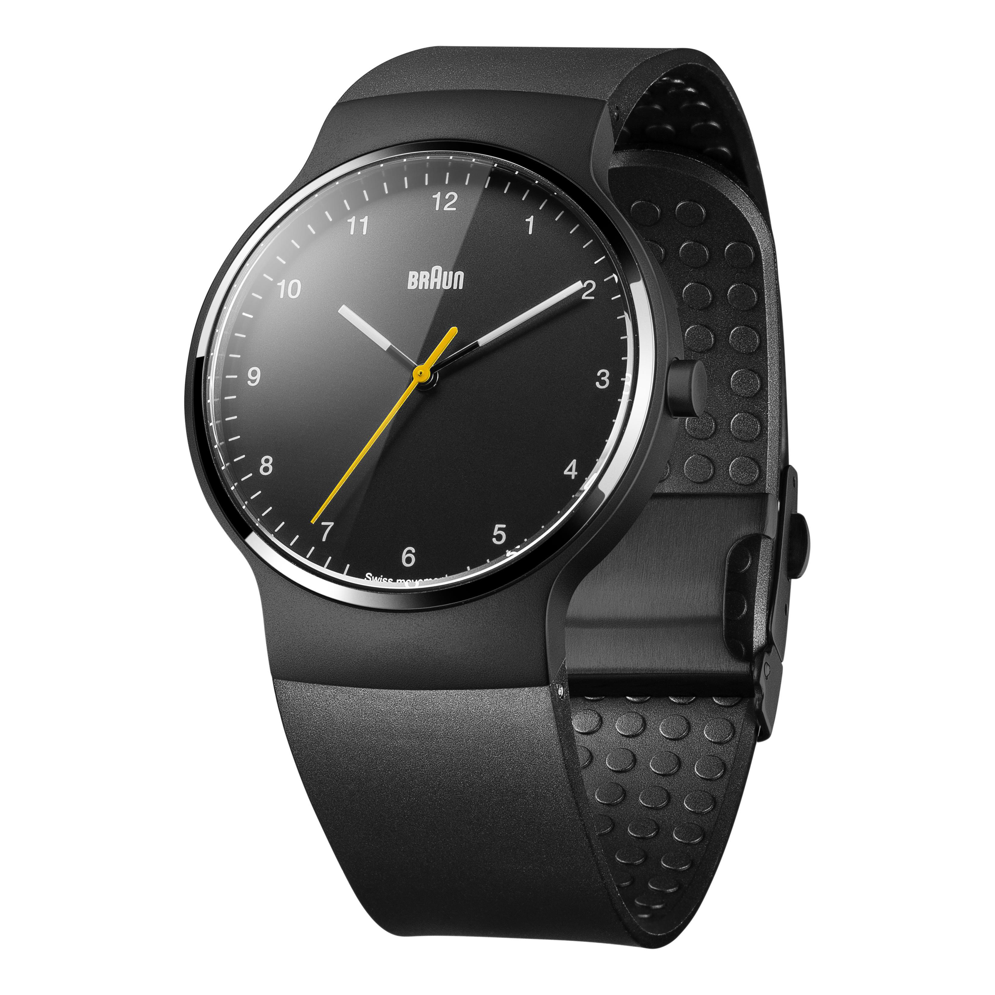 Schwarze Braun-Uhr mit schwarzem Zifferblatt, gelbem Sekundenzeiger und schwarzem Armband. Die Uhr liegt auf weißem Untergrund.