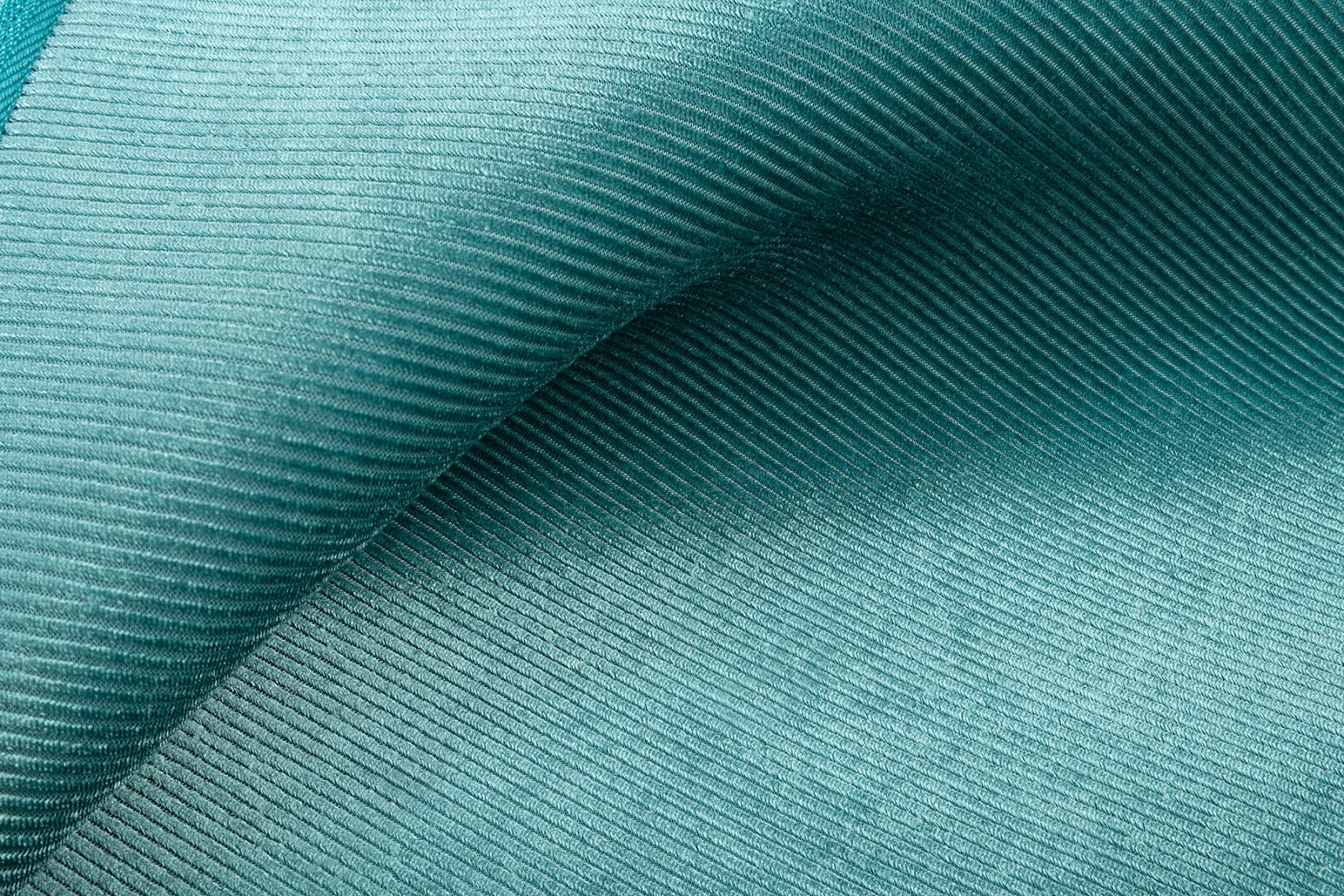 Primo piano di tessuto verde acqua con trama a coste, che mostra una piega curva.