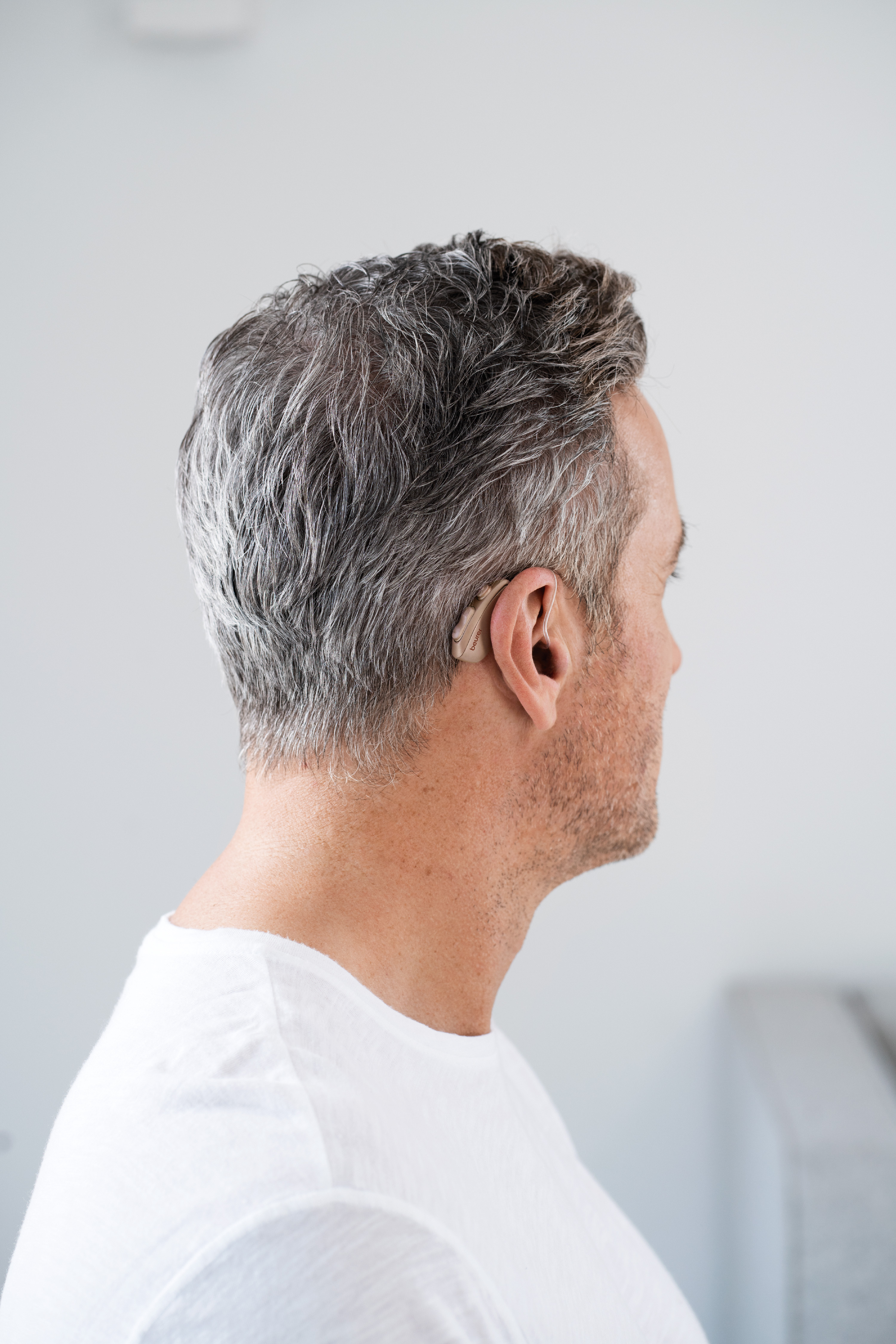 Mann mit grauem Haar, der ein Hörgerät hinter seinem rechten Ohr trägt.