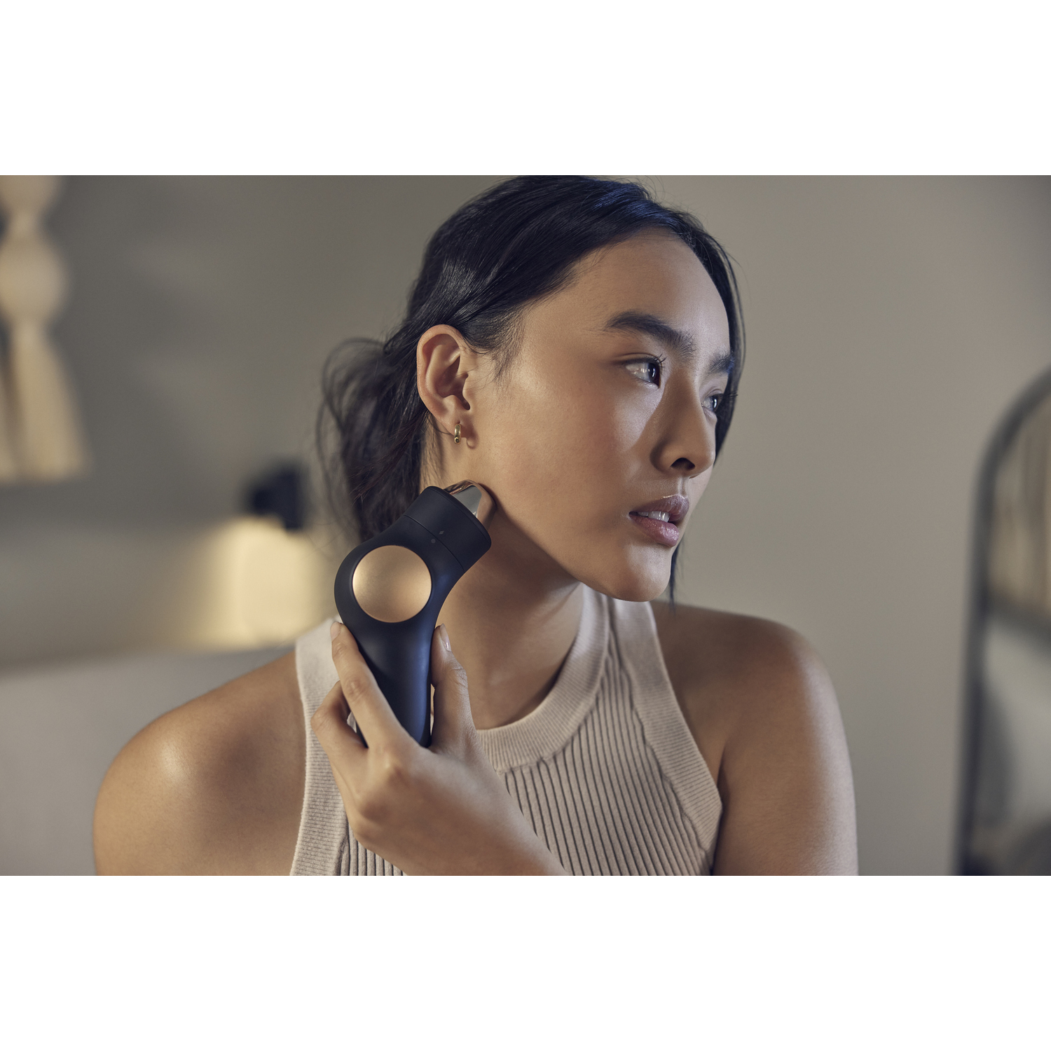 Mujer usando un dispositivo negro y dorado de depilación facial en su rostro.