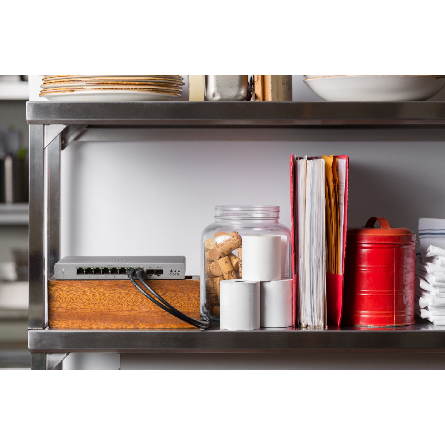 Estanterías con varios objetos: un switch de red, tarros con galletas y un contenedor rojo.