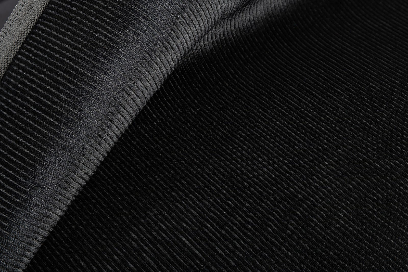 Nahaufnahme von schwarzem Stoff mit diagonaler, gerippter Textur.