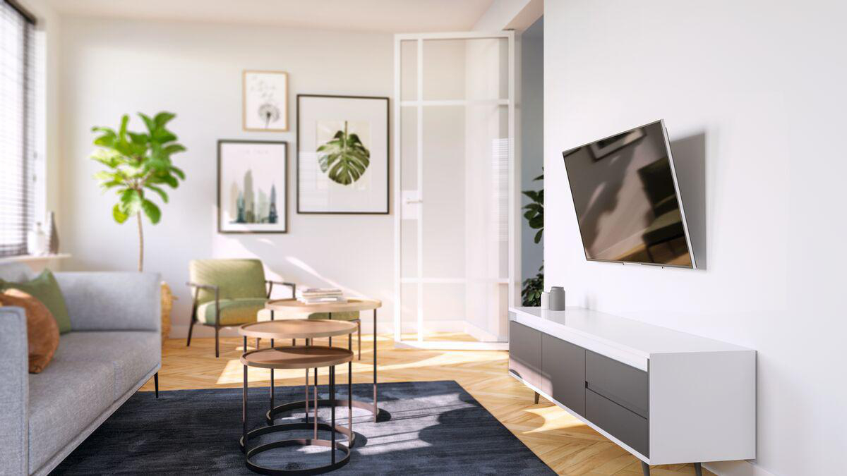 Wohnzimmer mit grauem Sofa, Couchtischen und Wand-TV.