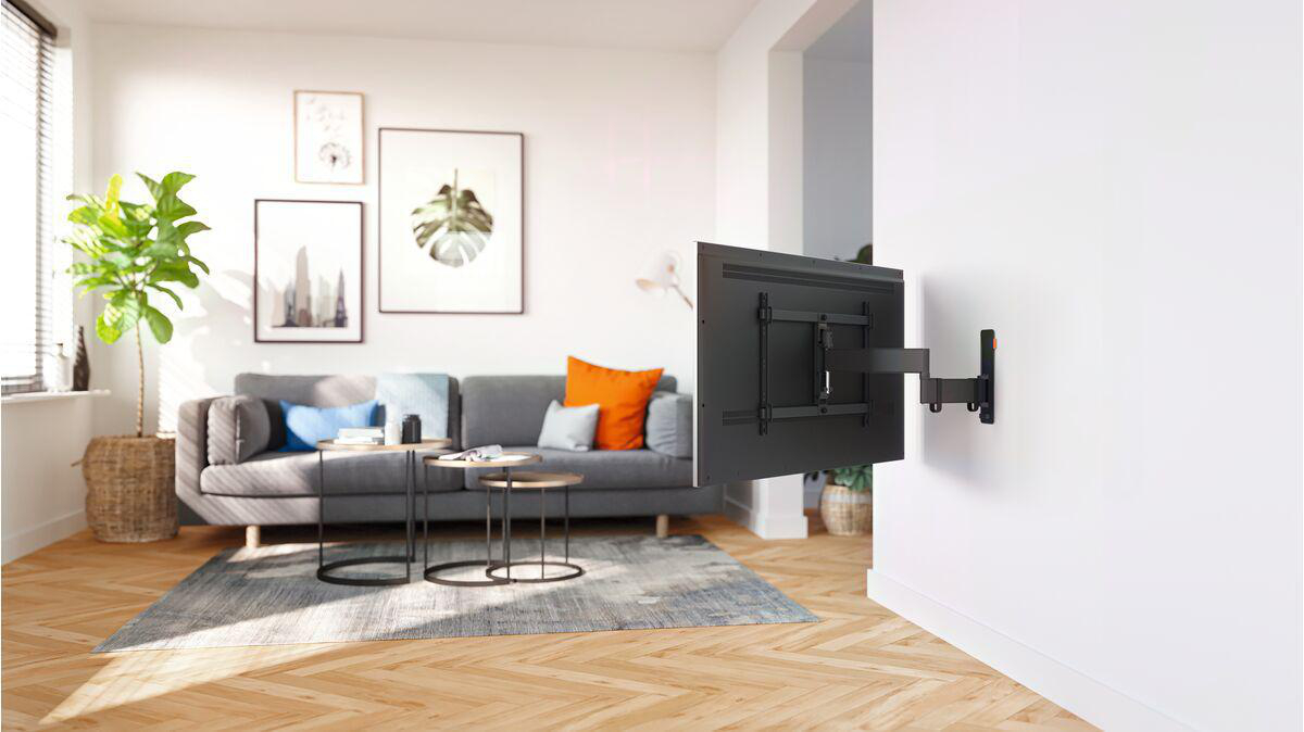 Wohnzimmer mit an der Wand montiertem Fernseher, Sofa und Dekoration.