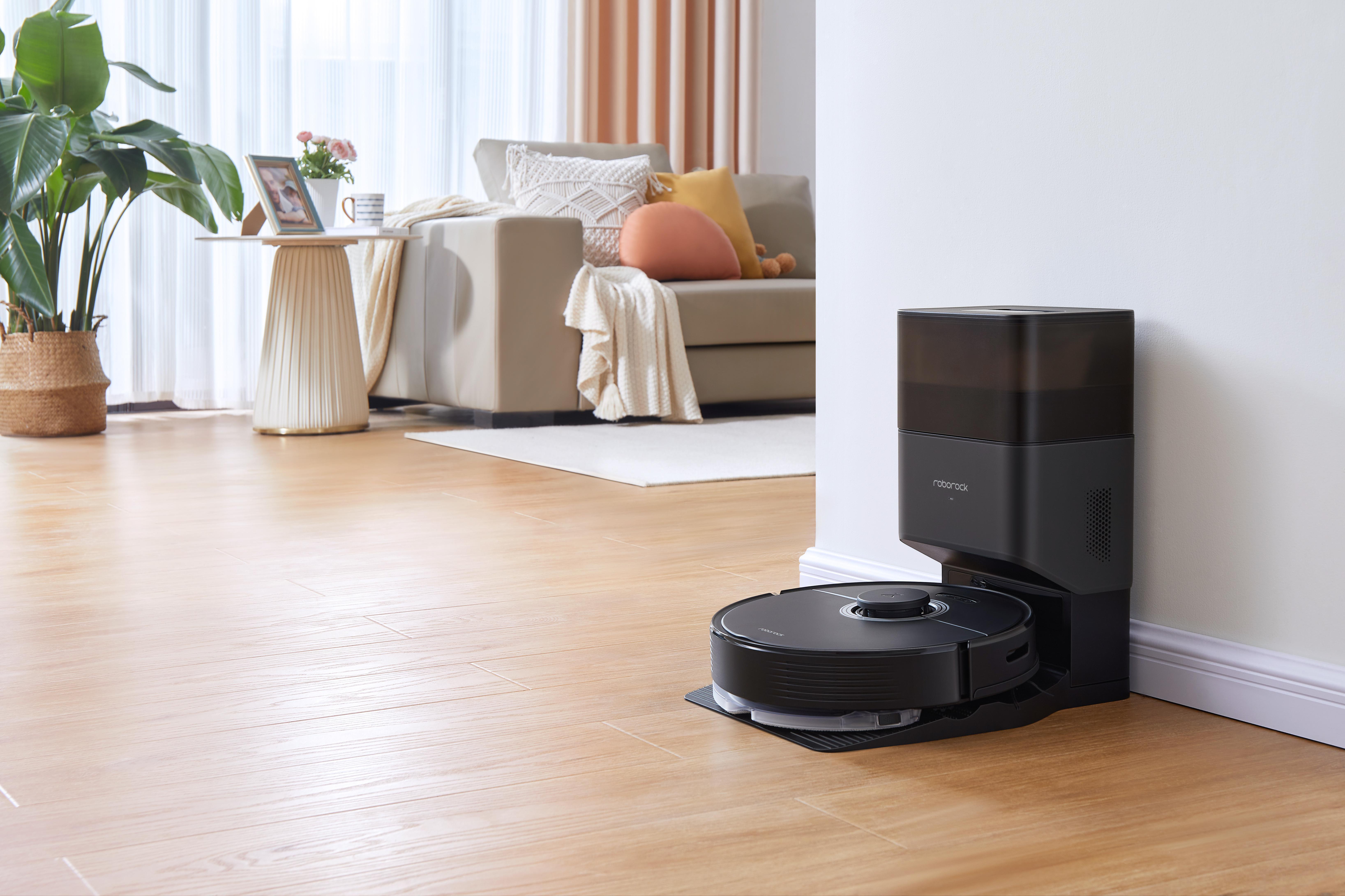 Roboter-Staubsauger auf dem Boden neben Ladestation. Modernes Wohnzimmer.