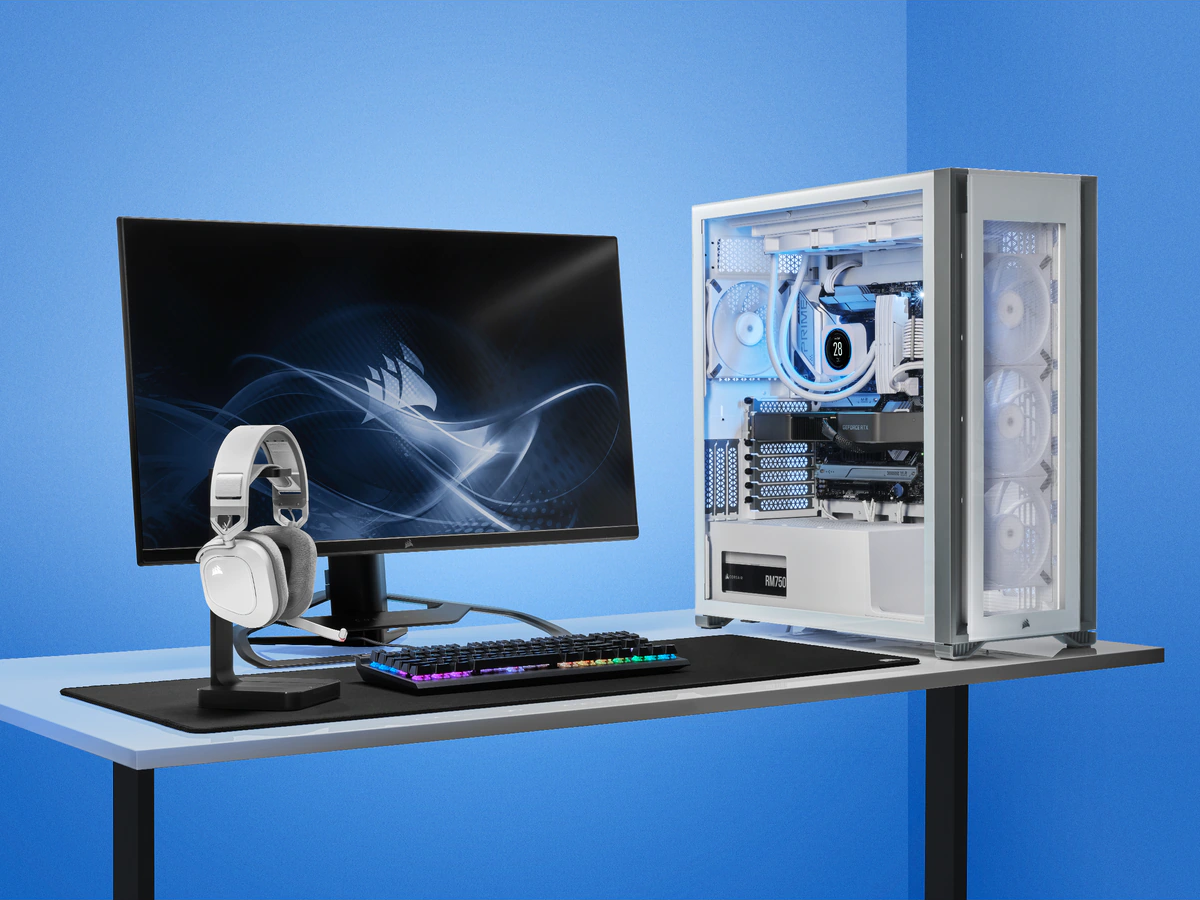 Ein Computer-Setup mit weißem Gehäuse, Monitor, Headset, Tastatur auf einem Schreibtisch, blauer Hintergrund.