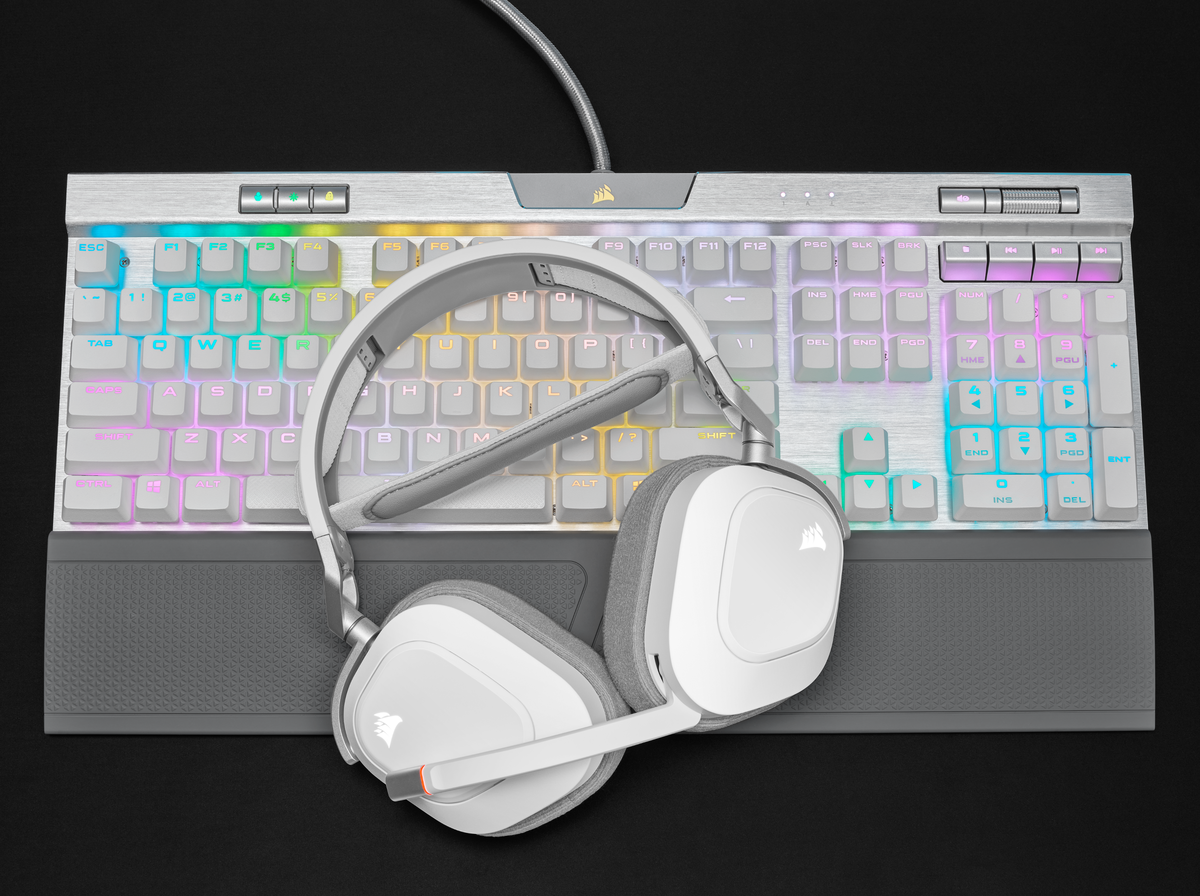 Eine weiße und graue Gaming-Tastatur mit einem weißen Headset darauf.