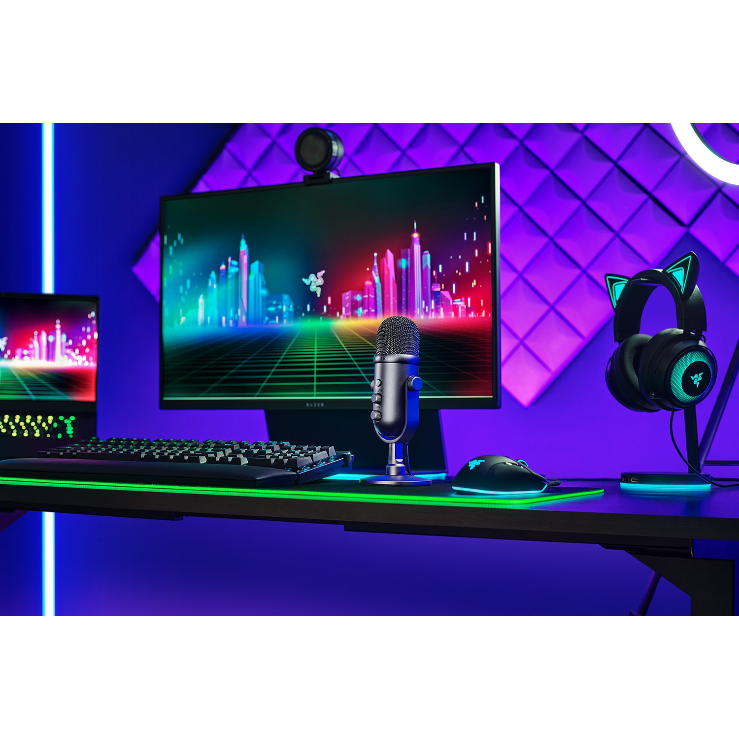 Configuración de juego con monitor, micrófono, teclado, ratón, auriculares y luces de colores.