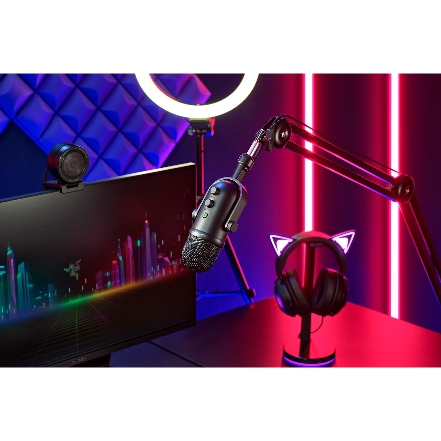 Micrófono, monitor, cámara y auriculares. El fondo está iluminado en púrpura y azul.