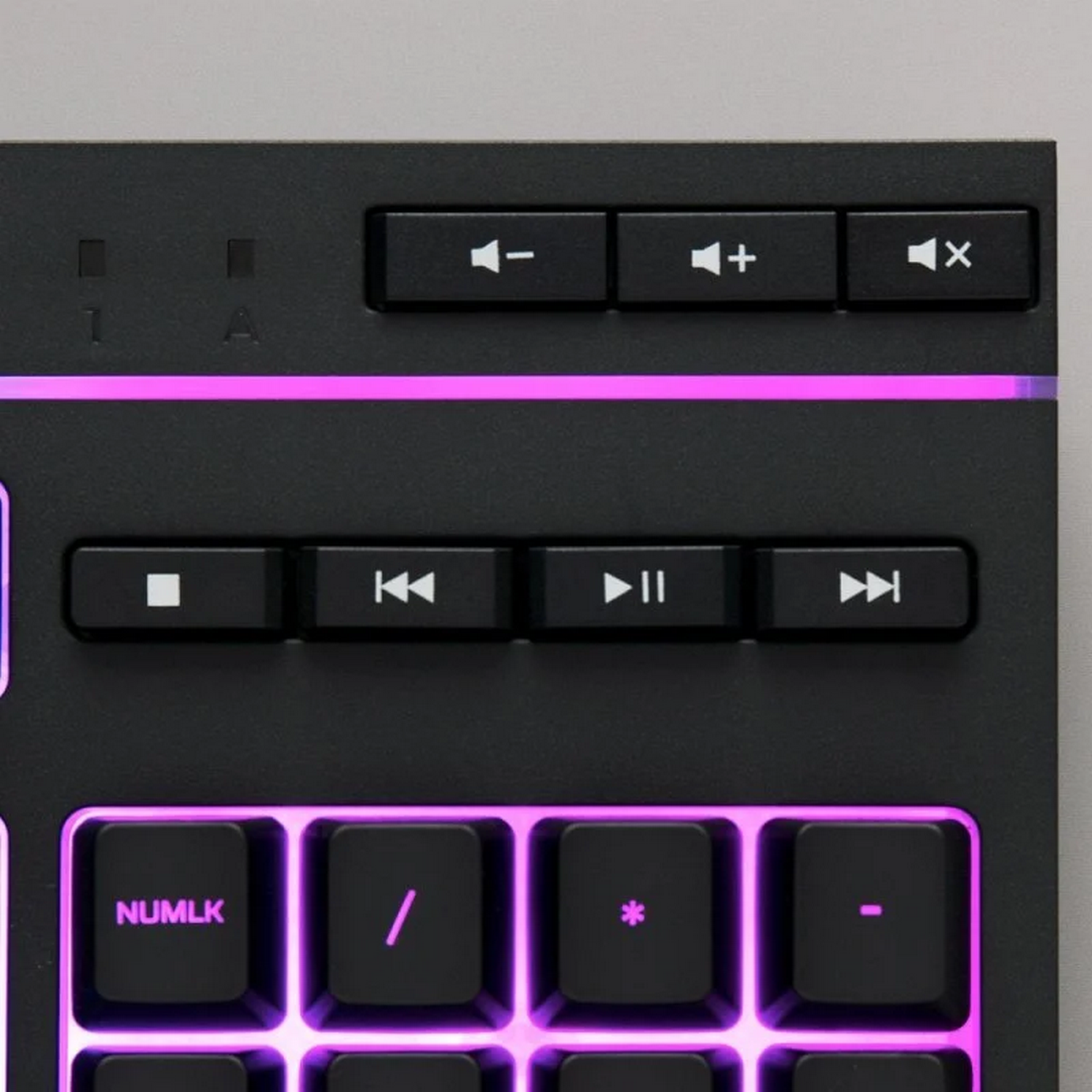 Primer plano de un teclado negro con teclas multimedia y teclado numérico iluminado en morado.