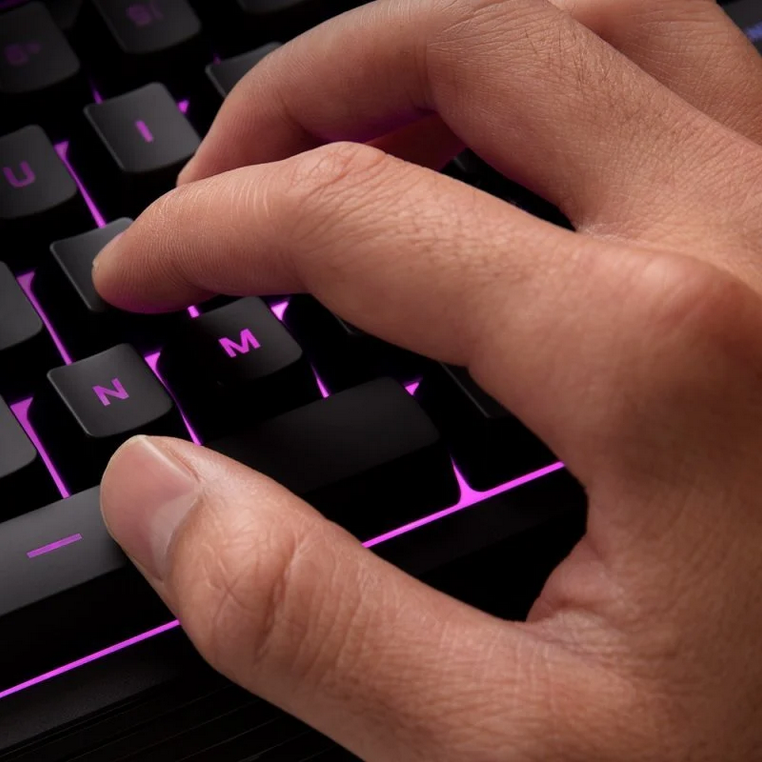 Una mano pulsa una tecla en un teclado negro con luces rosas.