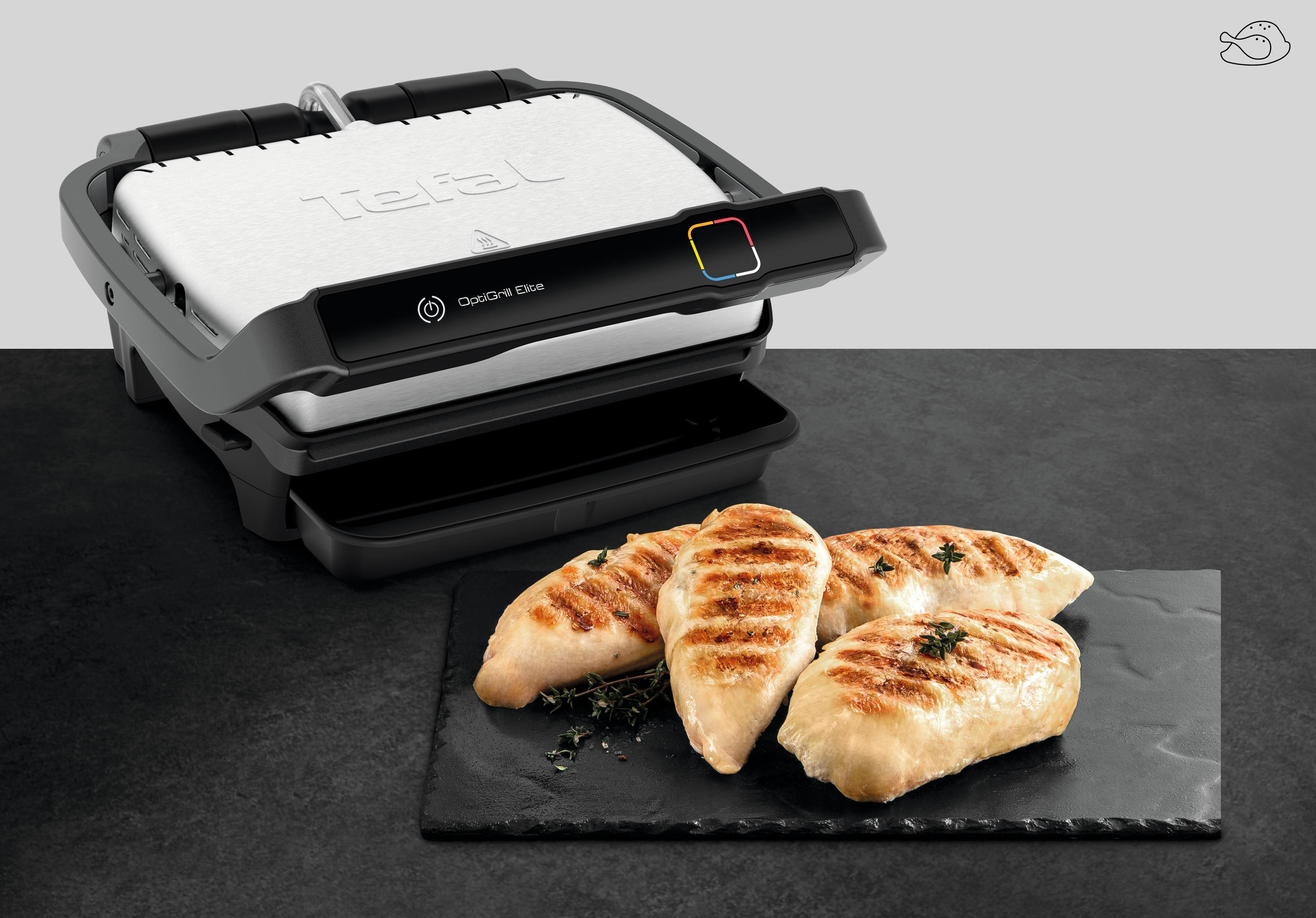 Schwarzer und silberner Grill mit gegrillten Hähnchenbrüsten auf einer Schieferplatte. Marke Tefal.