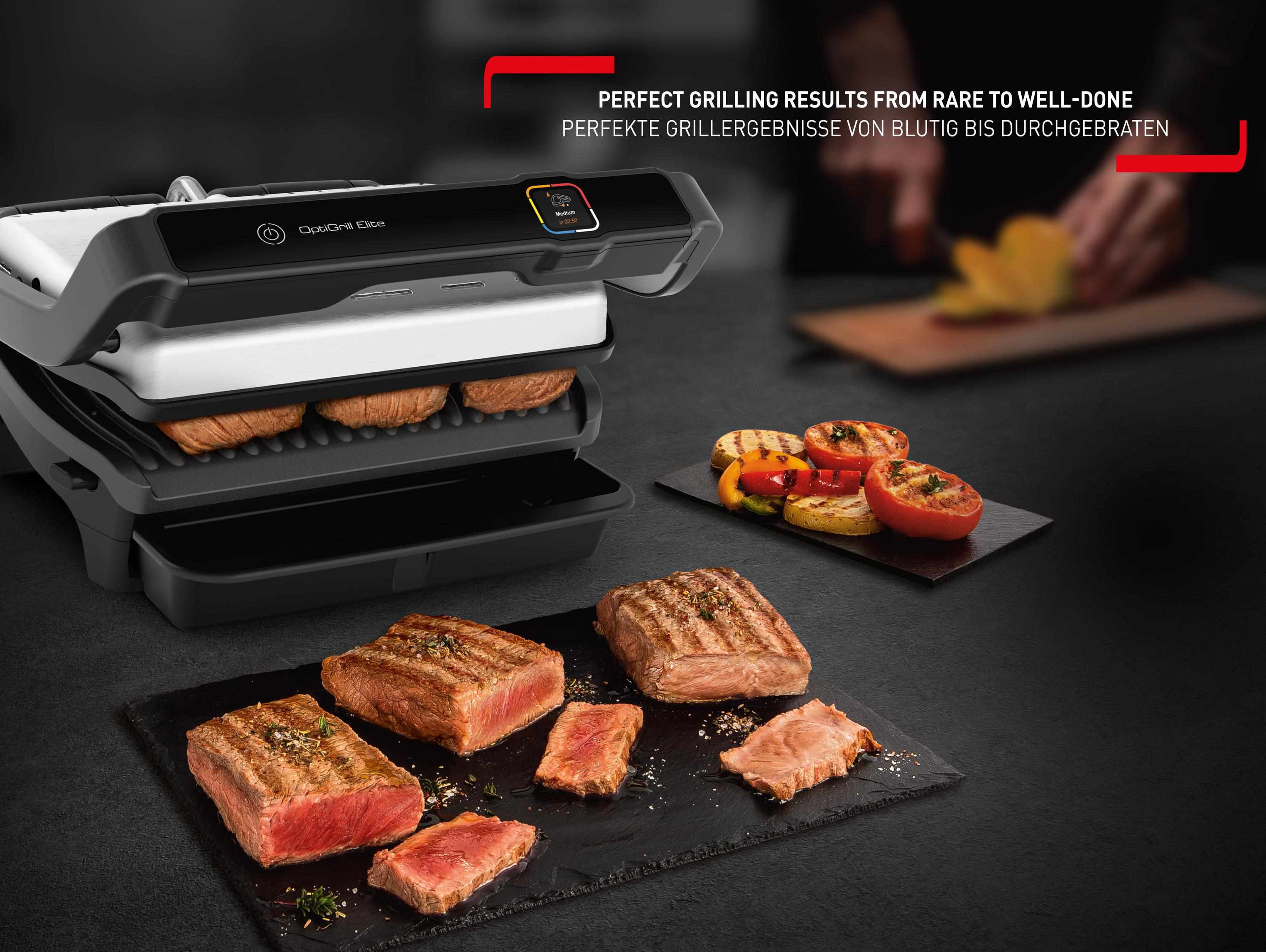 Grill mit gekochtem Essen, darunter Steaks und gegrilltes Gemüse. Schwarzer Hintergrund.