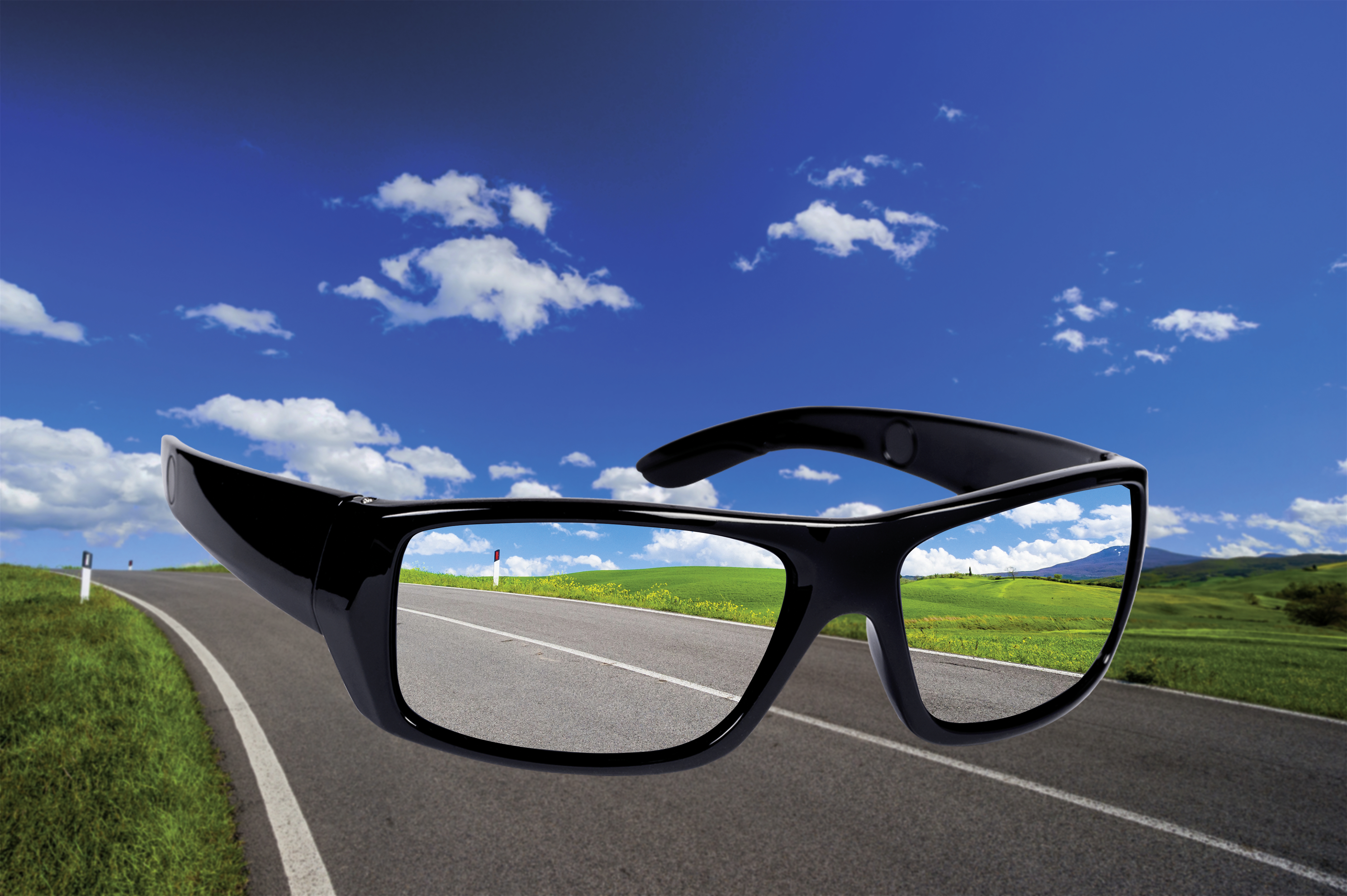 Schwarze Sonnenbrille mit Straße und Himmel, die sich in den Gläsern spiegeln.