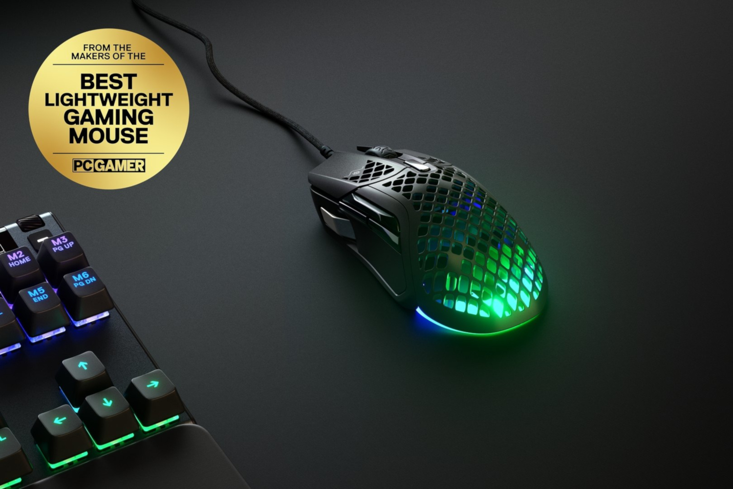 Gaming mouse on black surface. PC Gamer logo says 'Best Lightweight Gaming Mouse'. Keyboard keys visible.