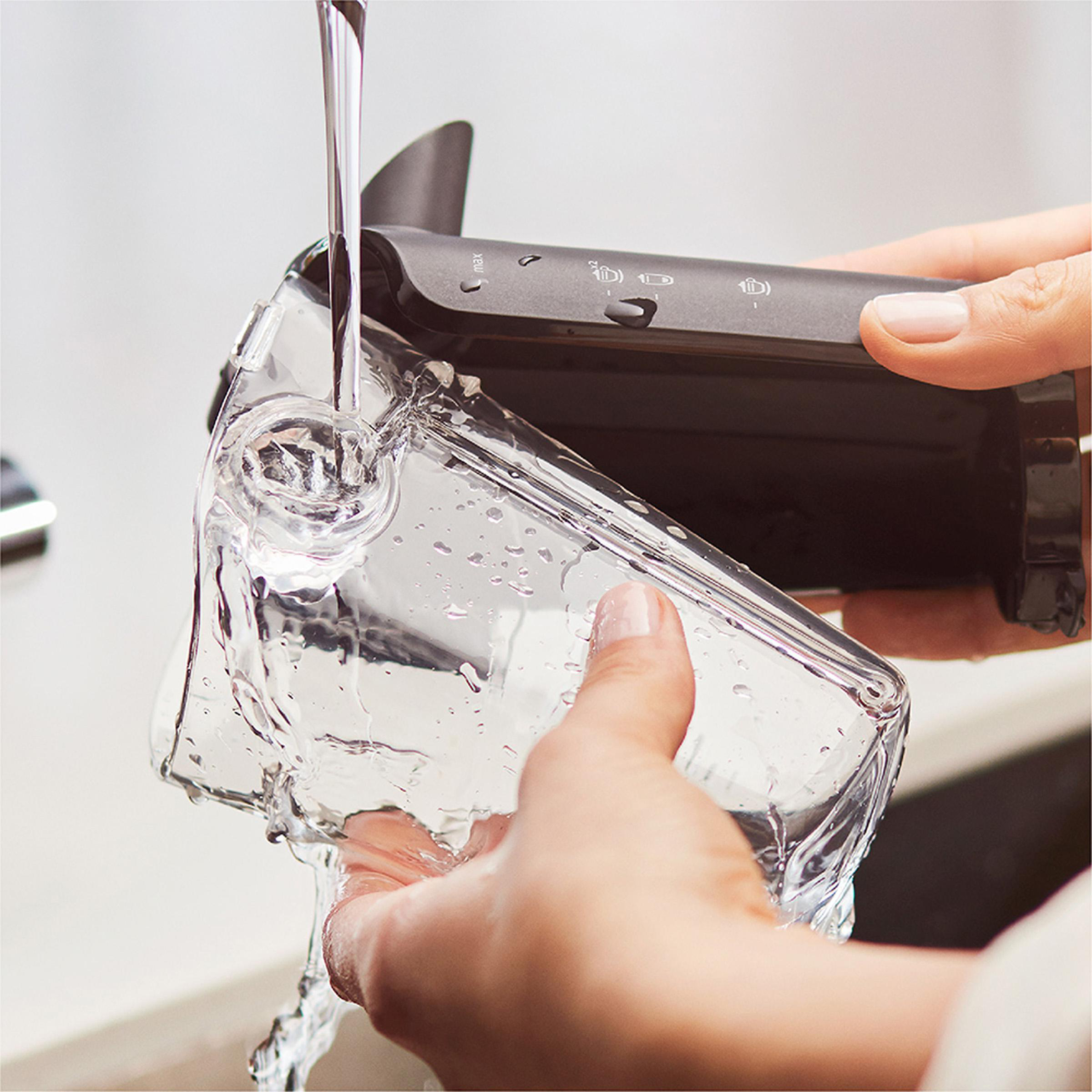 Wasser, das in einen transparenten Behälter gegossen wird, gehalten von Händen.