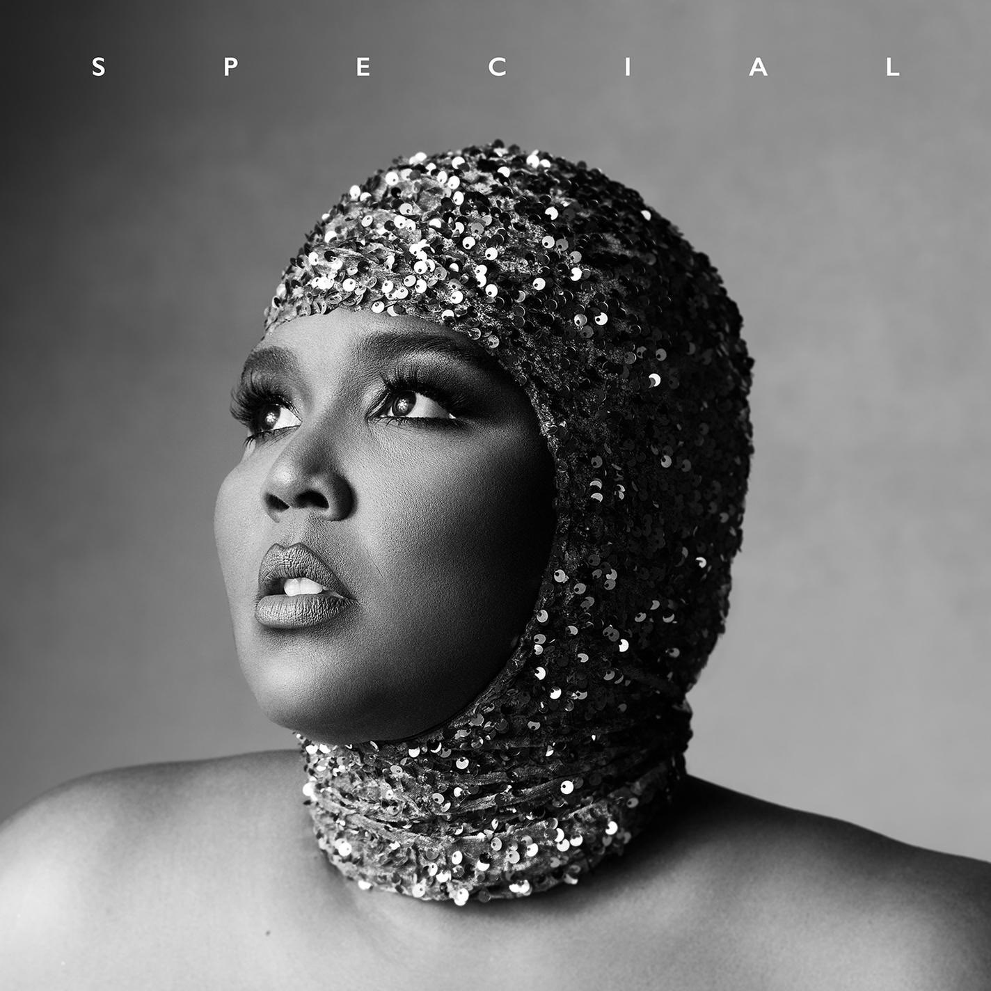 Lizzo in einer paillettenbesetzten Kopfbedeckung, blickt in einem Schwarz-Weiß-Foto nach oben.