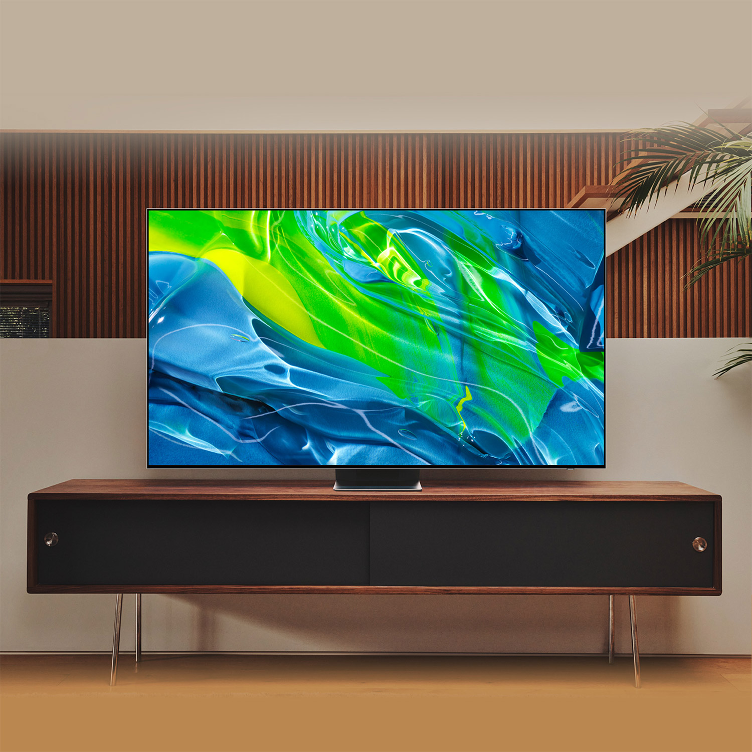Un televisor moderno con arte abstracto sobre un mueble de madera en una habitación con pared de madera.
