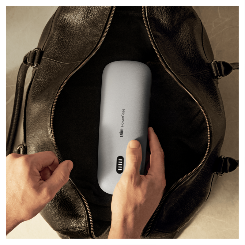 Hands putting a gray Braun PowerCase into a black leather bag.