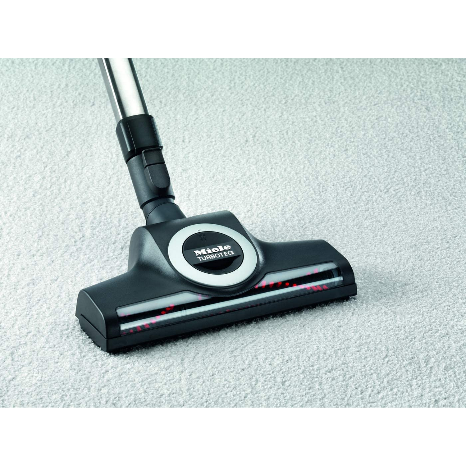 Un cabezal de vacío Miele TurboTec sobre una alfombra gris claro, con enfoque en el cabezal.