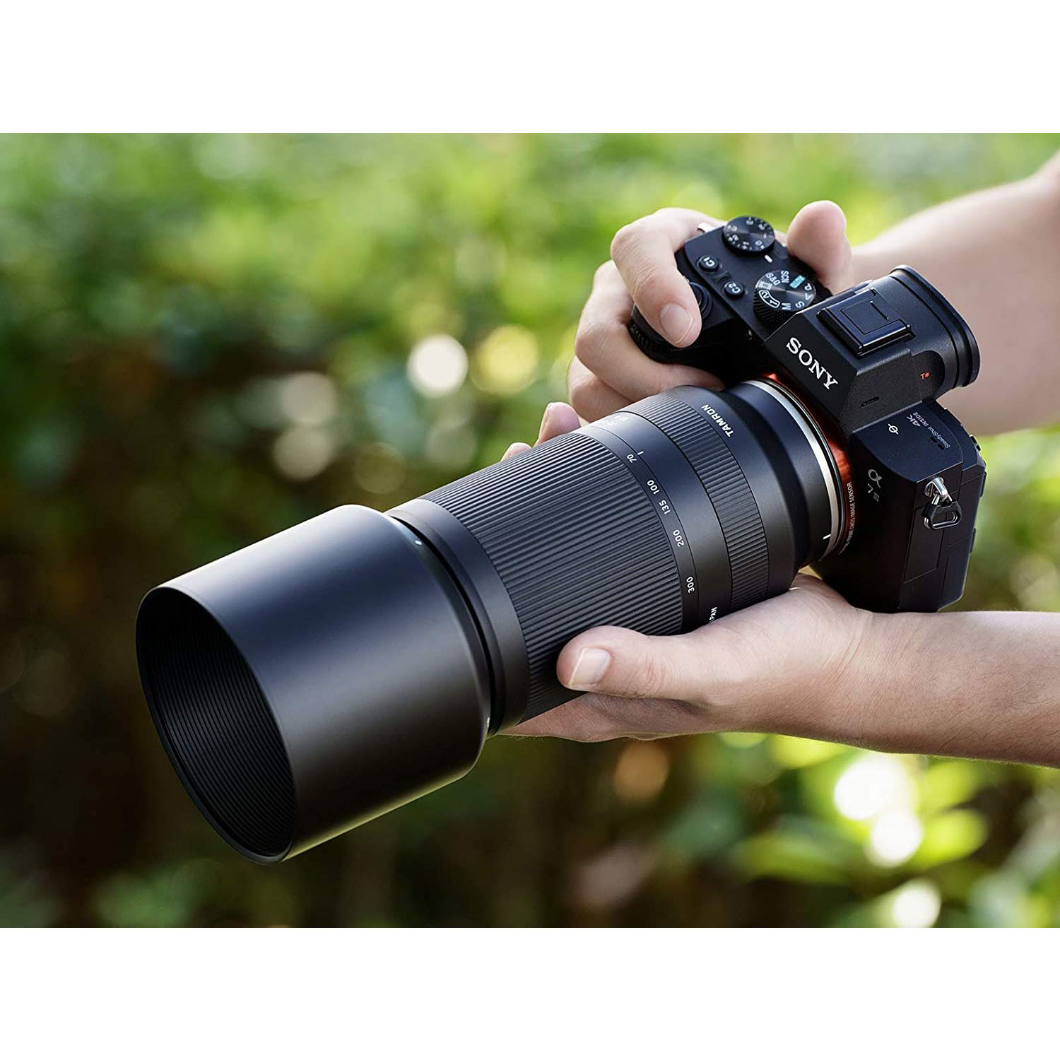 Persona che tiene una fotocamera con un obiettivo lungo, all'aperto.