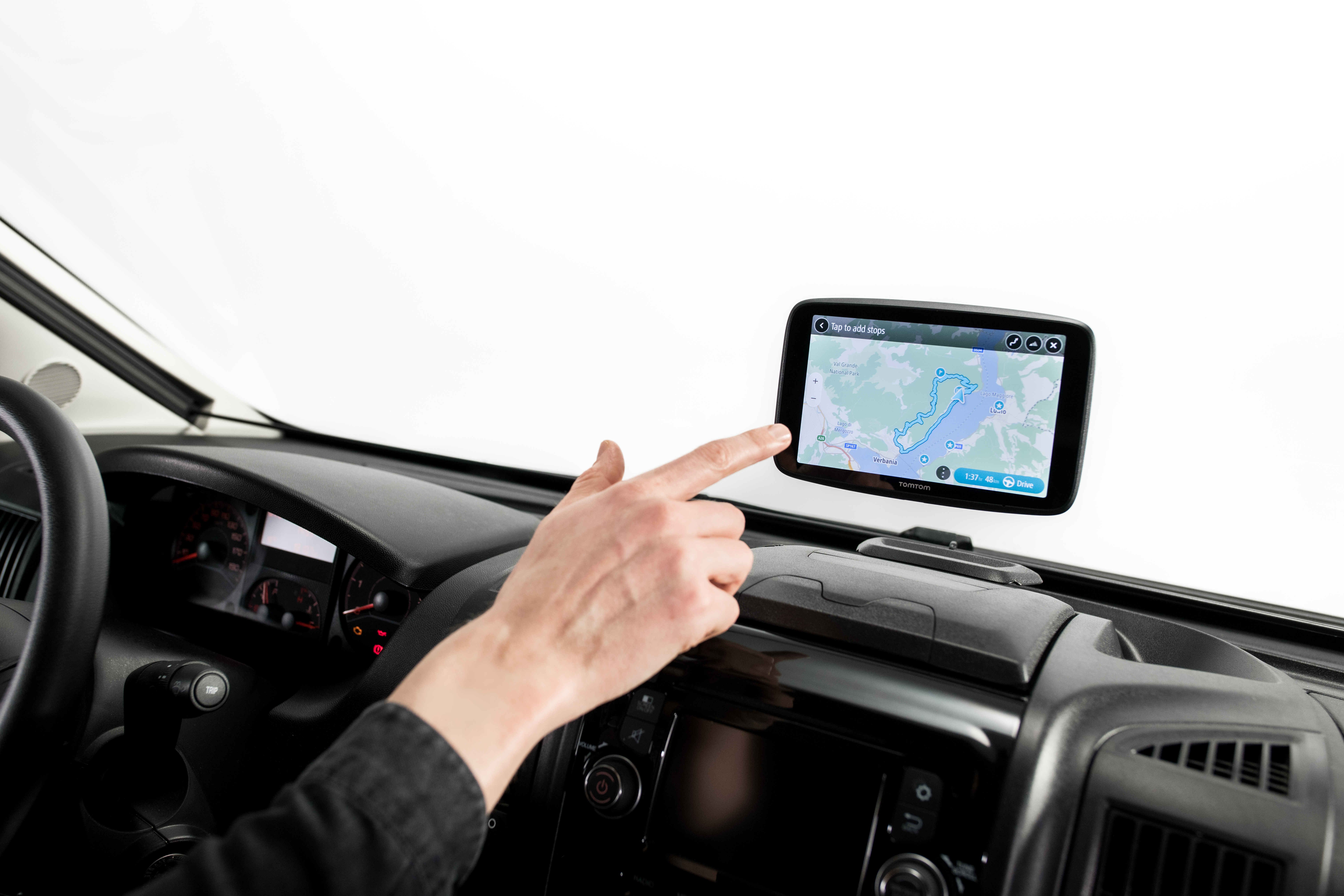 Die Hand einer Person zeigt auf ein GPS-Gerät in einem Auto. Der Bildschirm zeigt eine Straßenkarte.