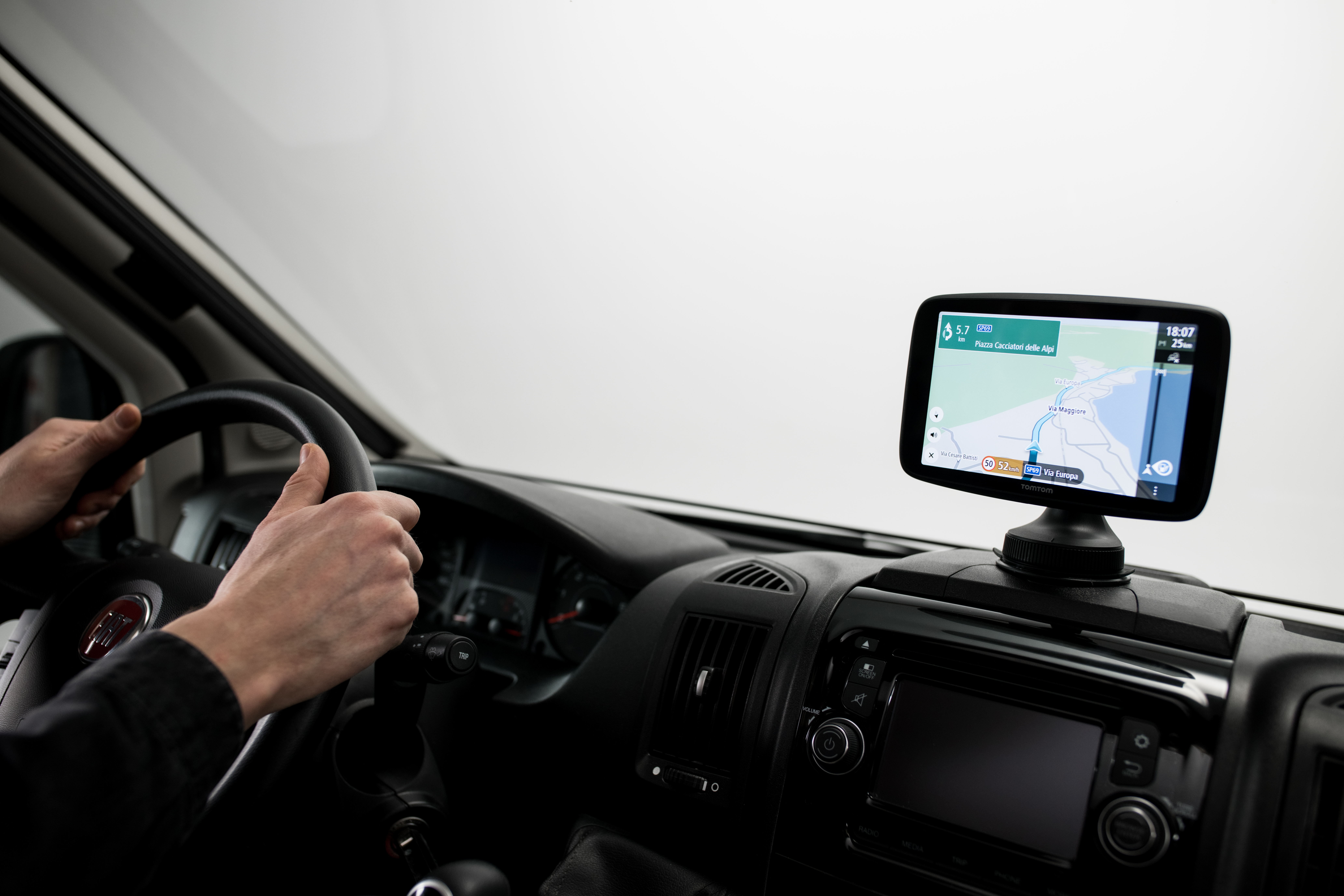 Hände am Lenkrad, Armaturenbrett mit GPS-Bildschirm im Van-Innenraum.