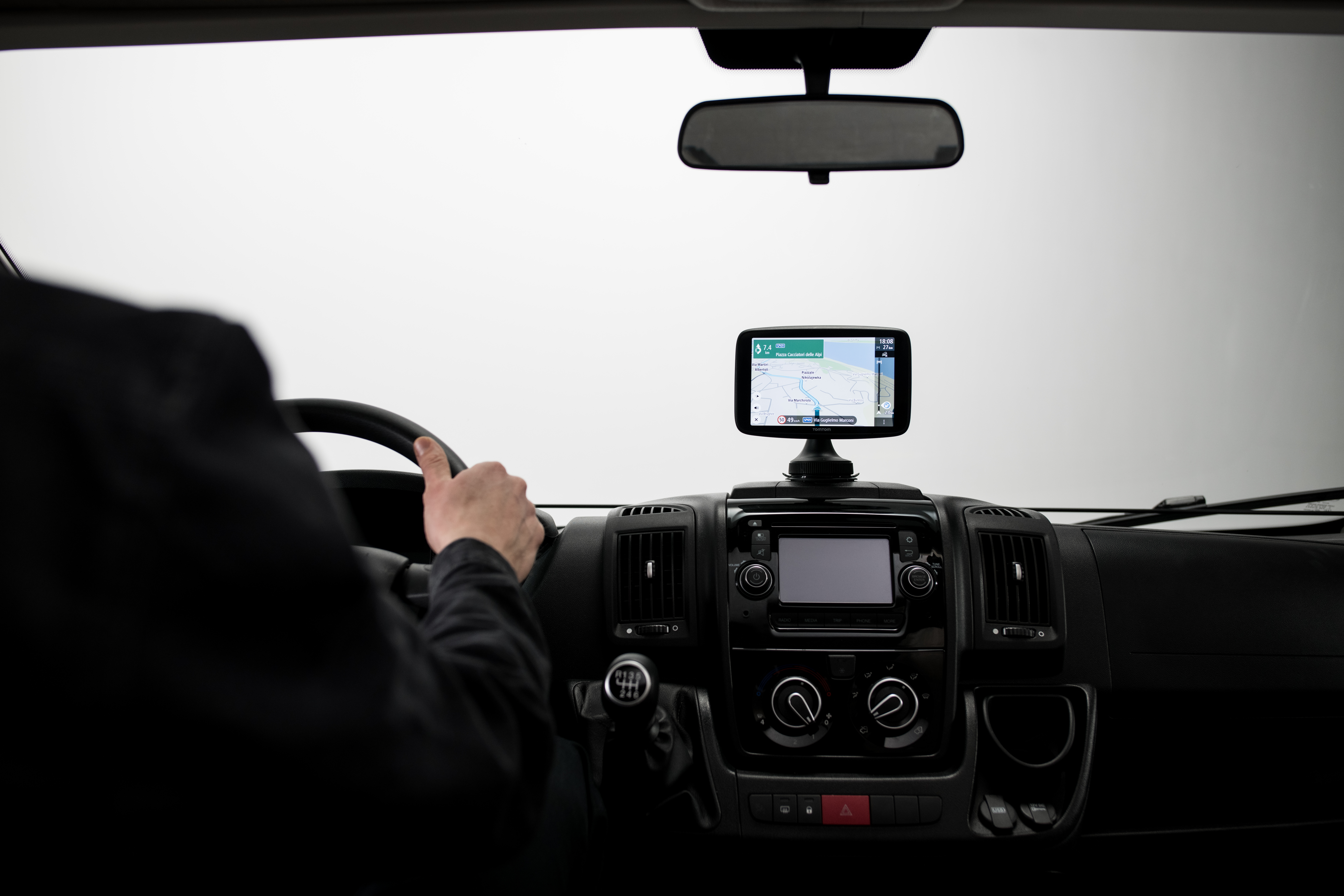 Autointerieur mit GPS auf dem Armaturenbrett und einer Person am Lenkrad.