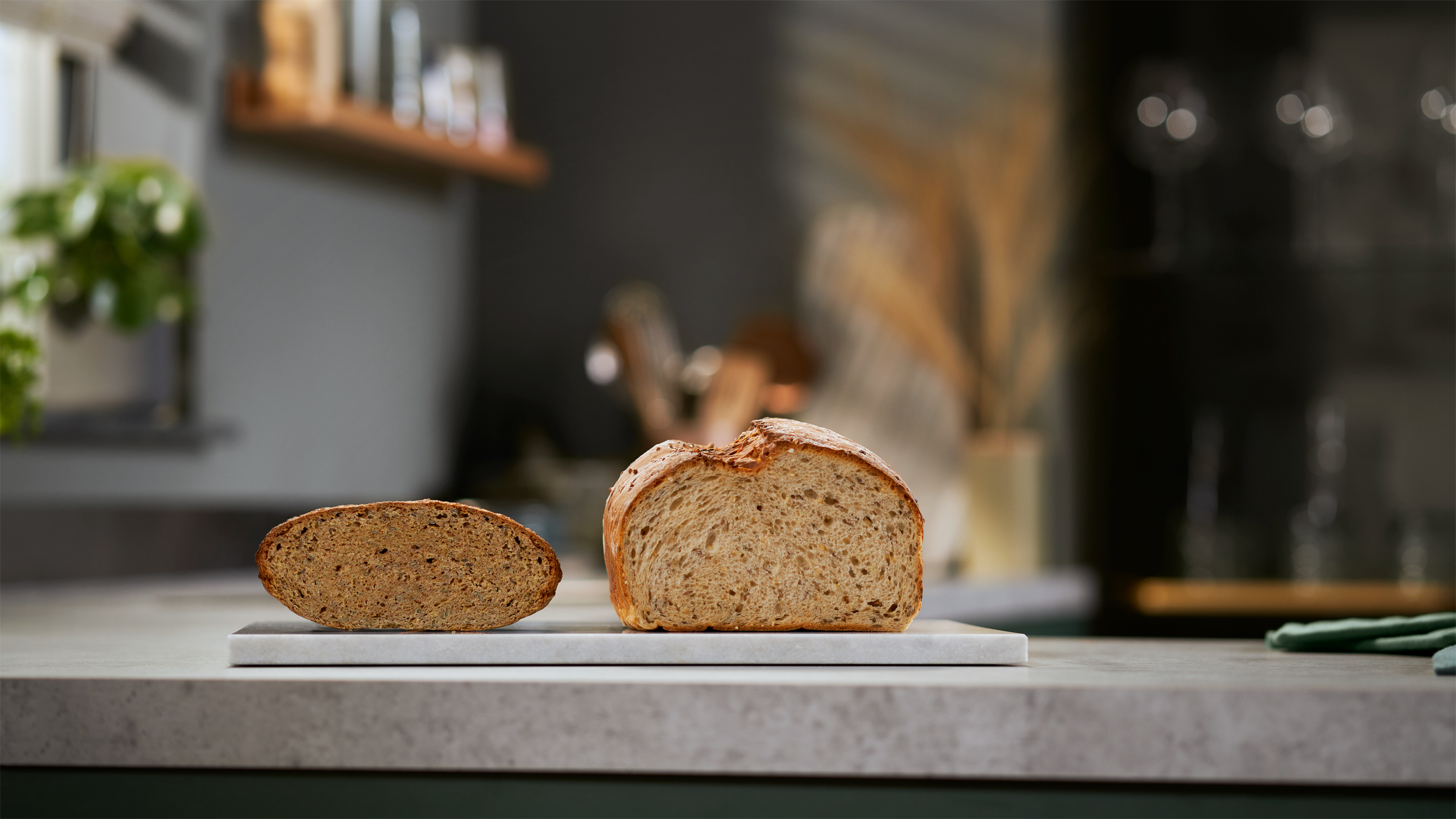 Twee sneetjes brood op een wit oppervlak. Eén is een hele snee, de andere is half. Keukenachtergrond.