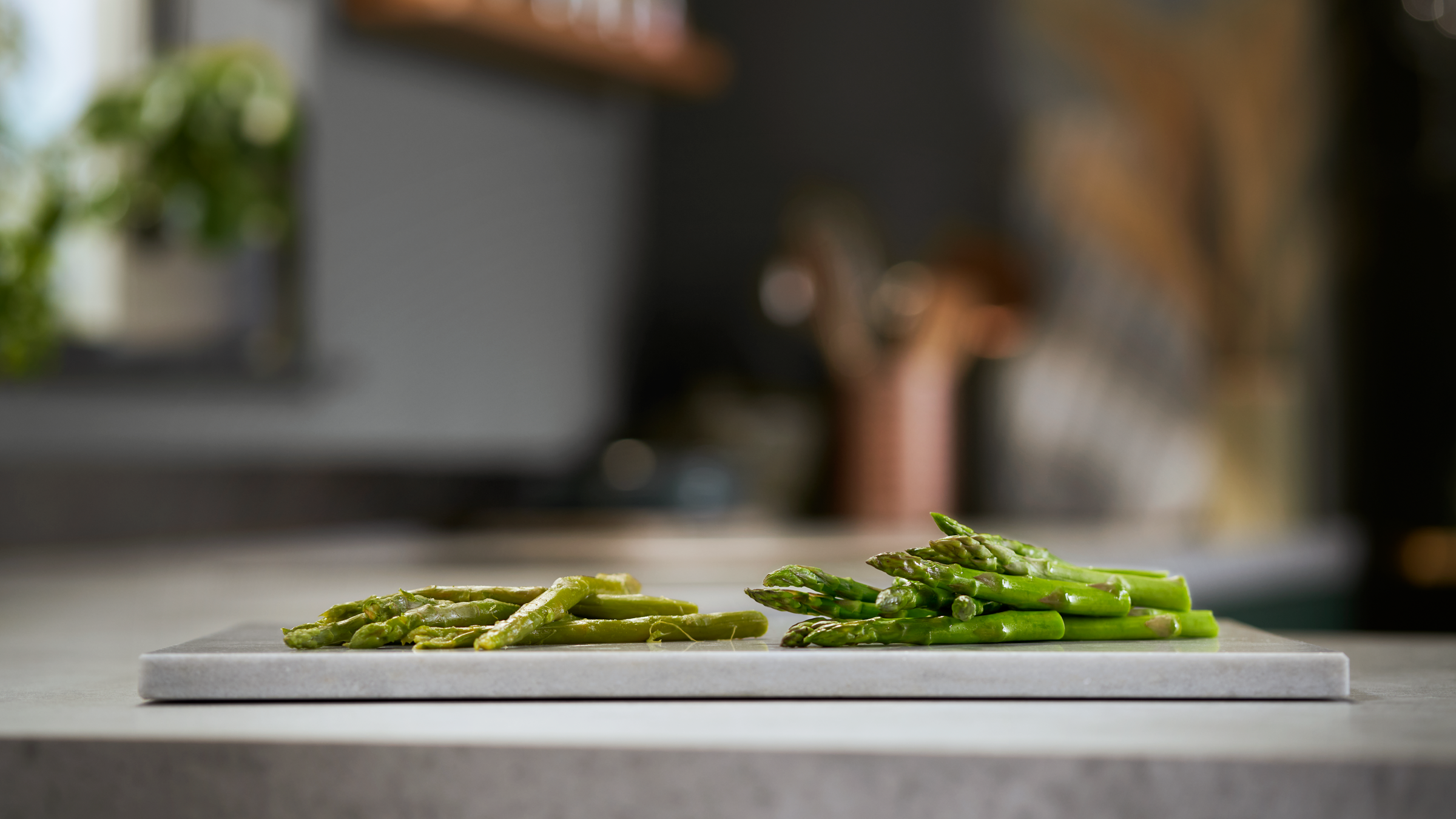 Asperges op een marmeren plank, sommige gesneden en hele, in de keuken.