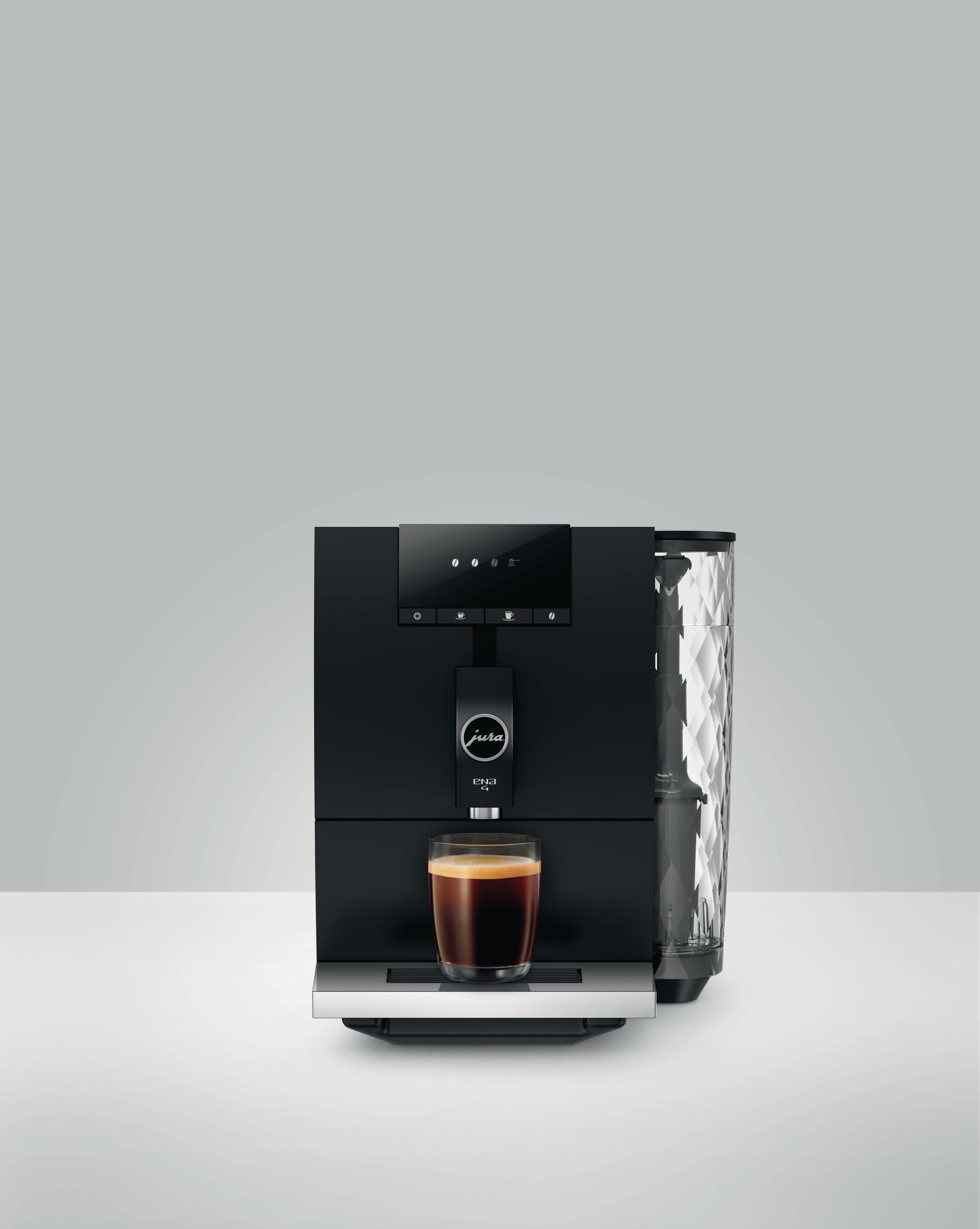 Schwarze Kaffeemaschine mit zwei Tassen und einem Glas Kaffee. Der Hintergrund ist eine verschwommene Stadtlandschaft.