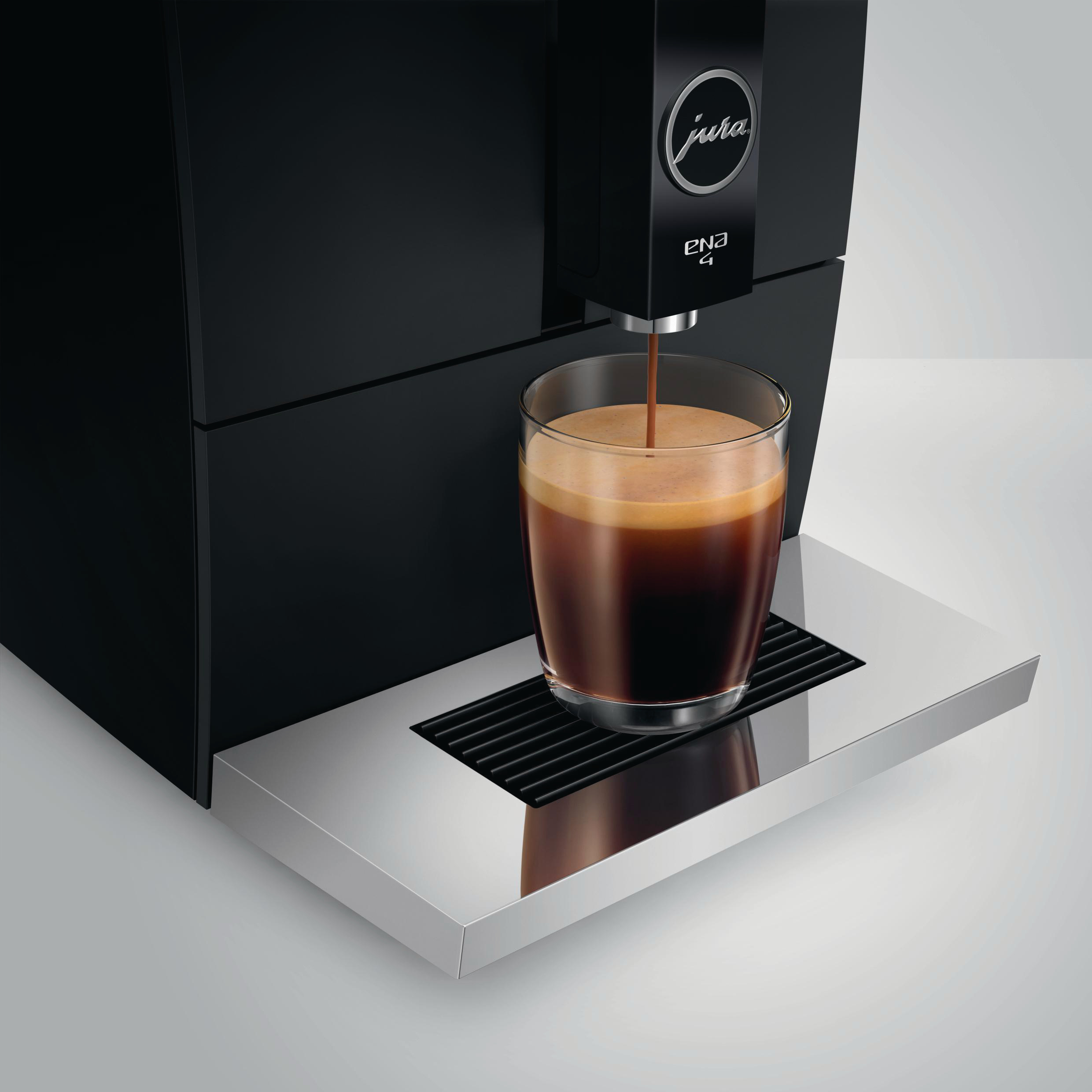 Schwarze Jura Kaffeemaschine, die Kaffee in ein Glas ausgibt.