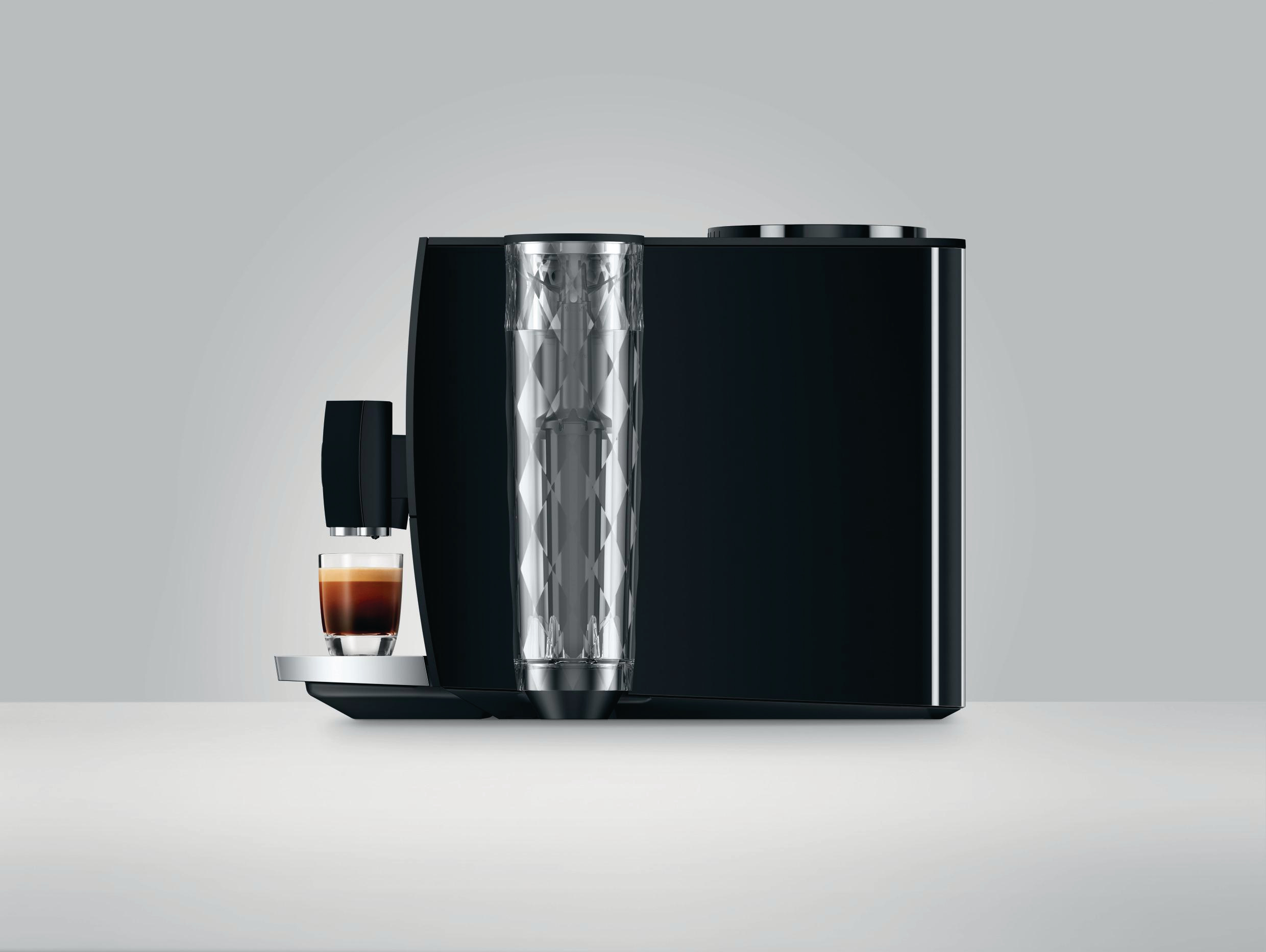 Schwarze Jura Kaffeemaschine mit gläsernem Wasserbehälter und einer Tasse Kaffee davor.