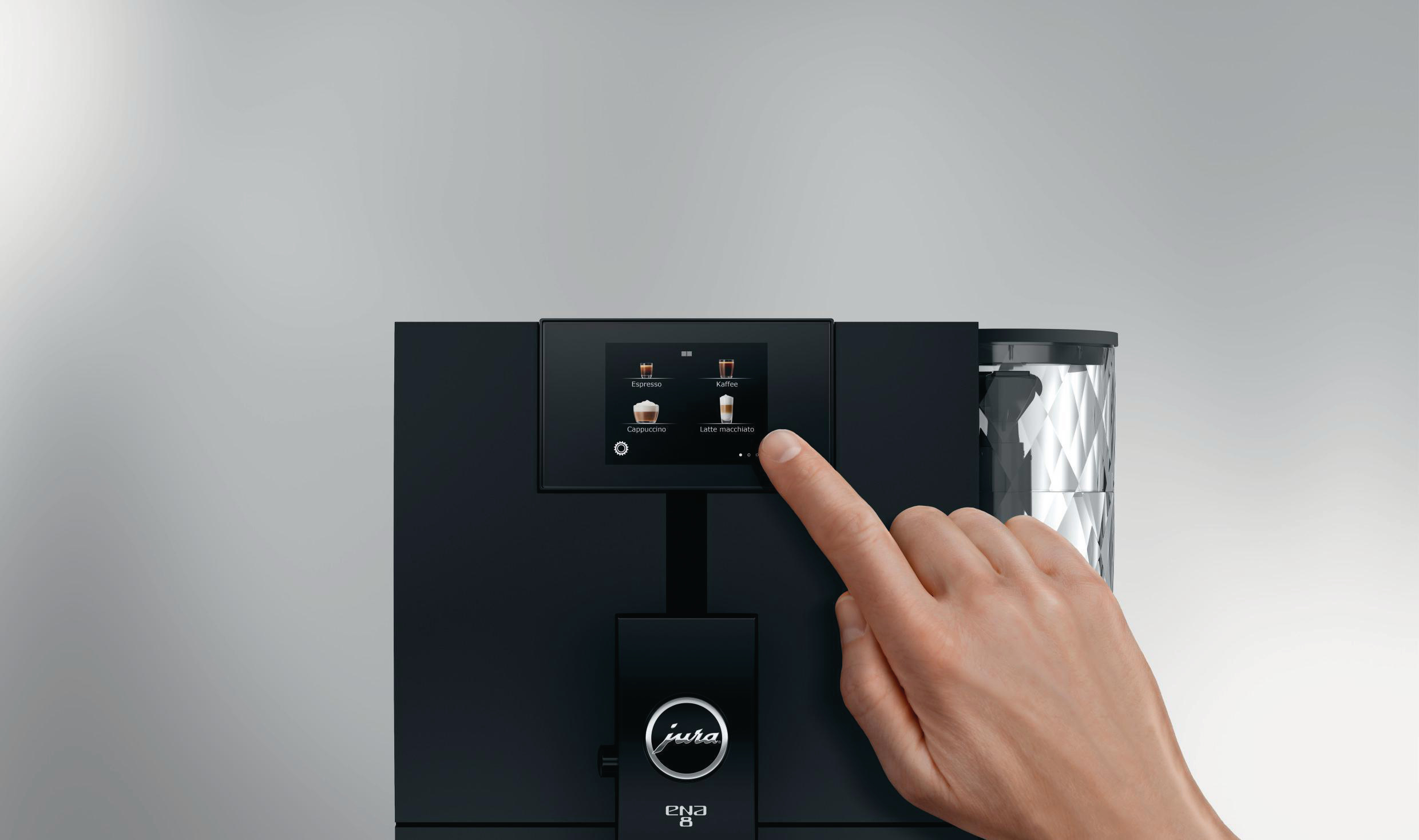 Nahaufnahme einer Hand, die einen Touchscreen an einer schwarzen Jura ENA 8 Kaffeemaschine berührt.