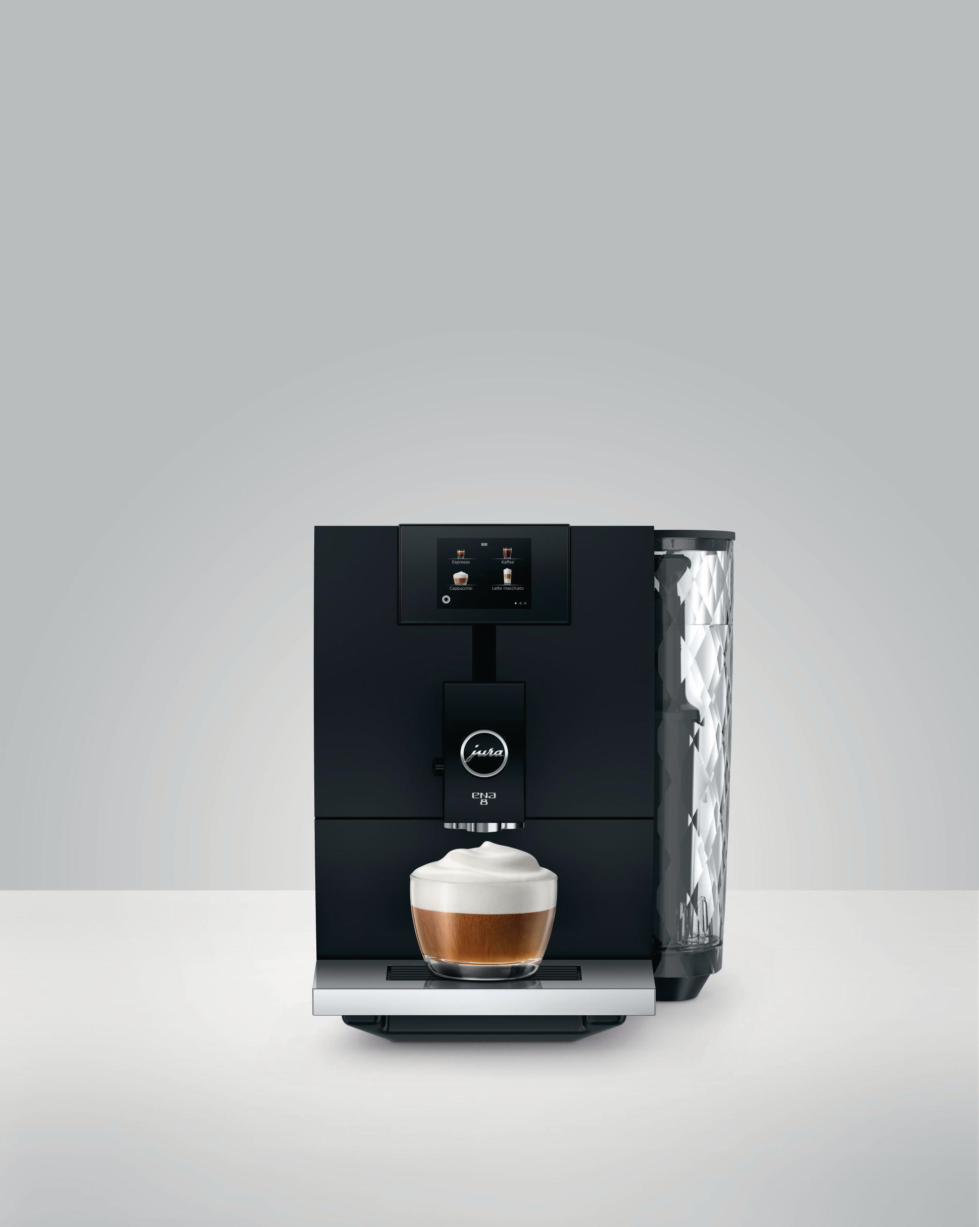 Schwarze Kaffeemaschine mit einer Tasse Kaffee und Milchschaum, auf weißem Hintergrund.