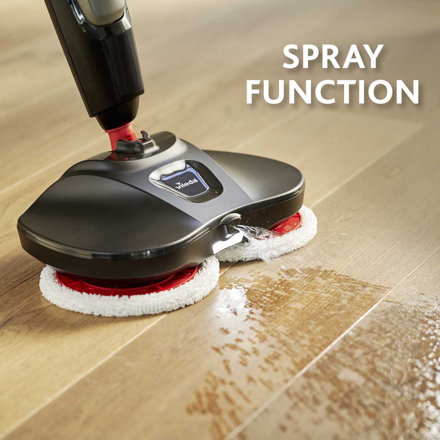 Una scopa a vapore nera pulisce un pavimento in legno, con funzione spray attiva.