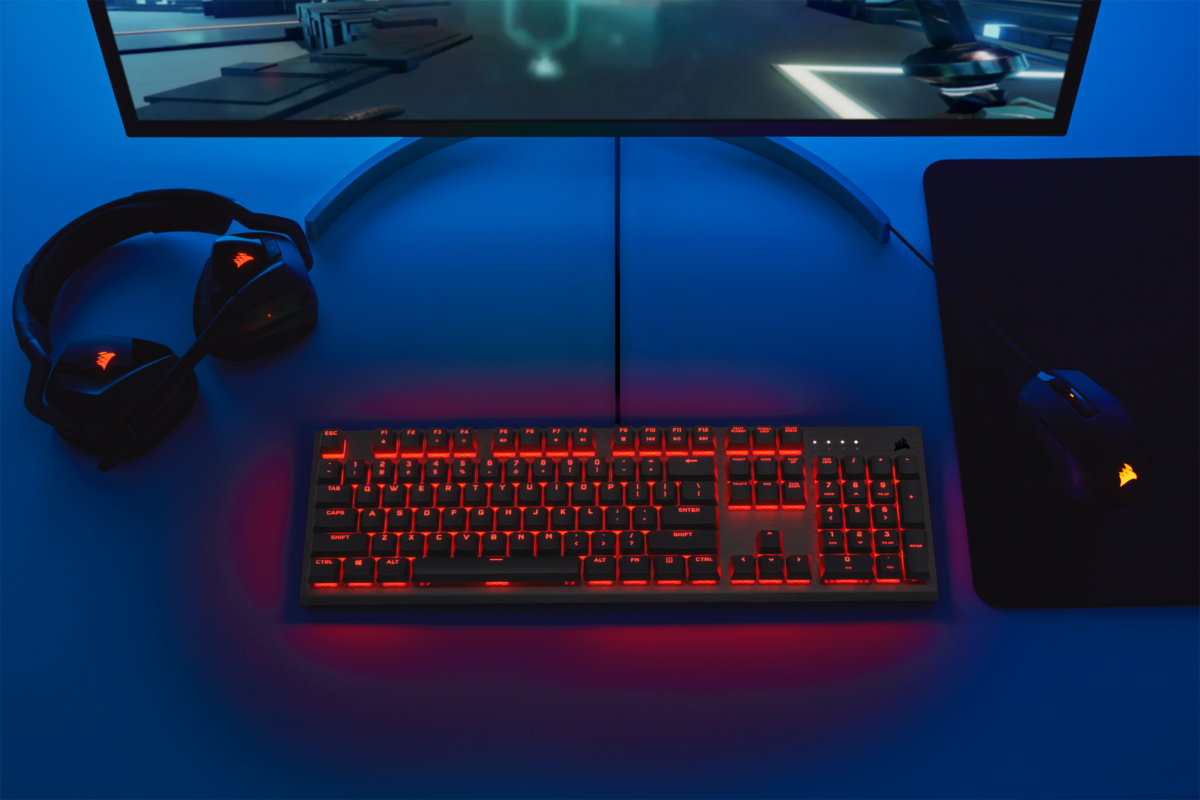 Ein Gaming-Setup mit rot beleuchteter Tastatur, Headset und Maus auf einem blauen Schreibtisch.