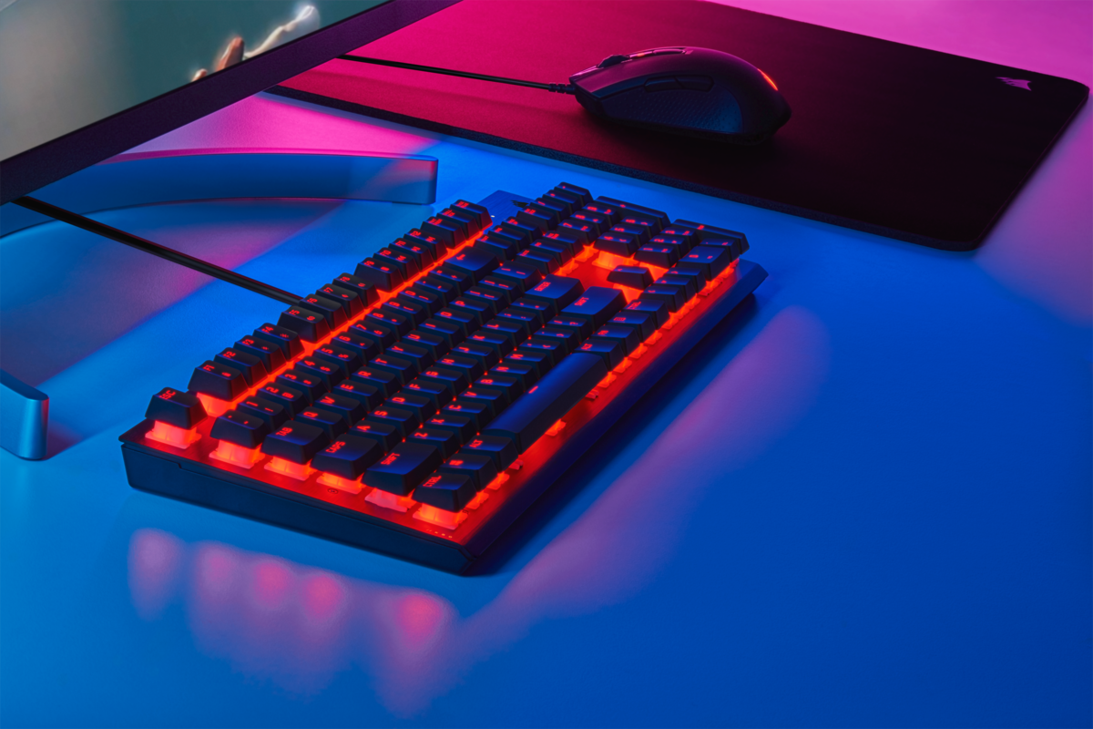 Rot hinterleuchtete Tastatur auf dem Schreibtisch, Maus und Mauspad sichtbar.
