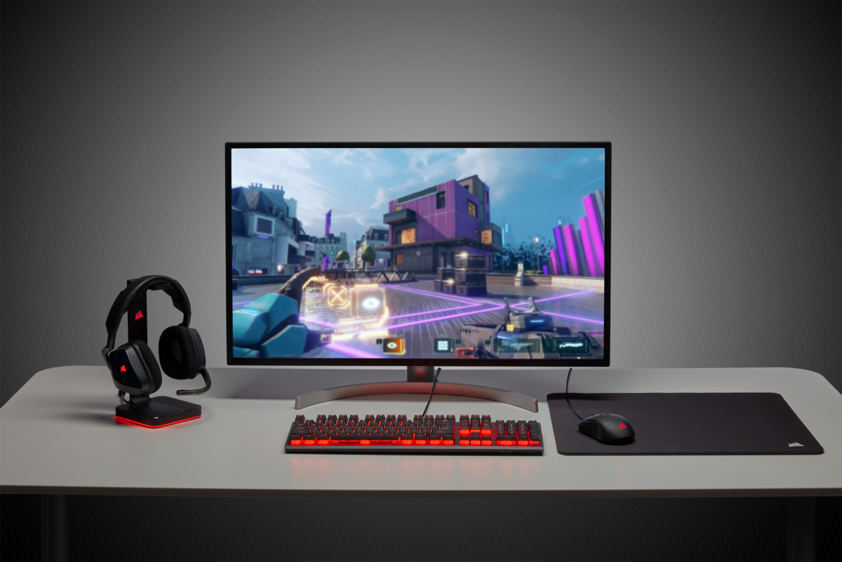 Gaming-Setup mit Monitor, Tastatur, Maus, Headset auf einem Schreibtisch.
