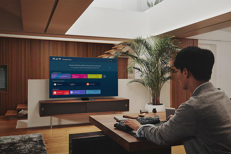 Mann, der einen Laptop verwendet, der mit einem Fernseher verbunden ist. Zeigt einen Bildschirm mit PC auf TV und Online-Apps.