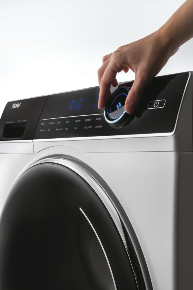 Une main tourne le bouton d'une machine à laver Haier. L'écran affiche 80:00.